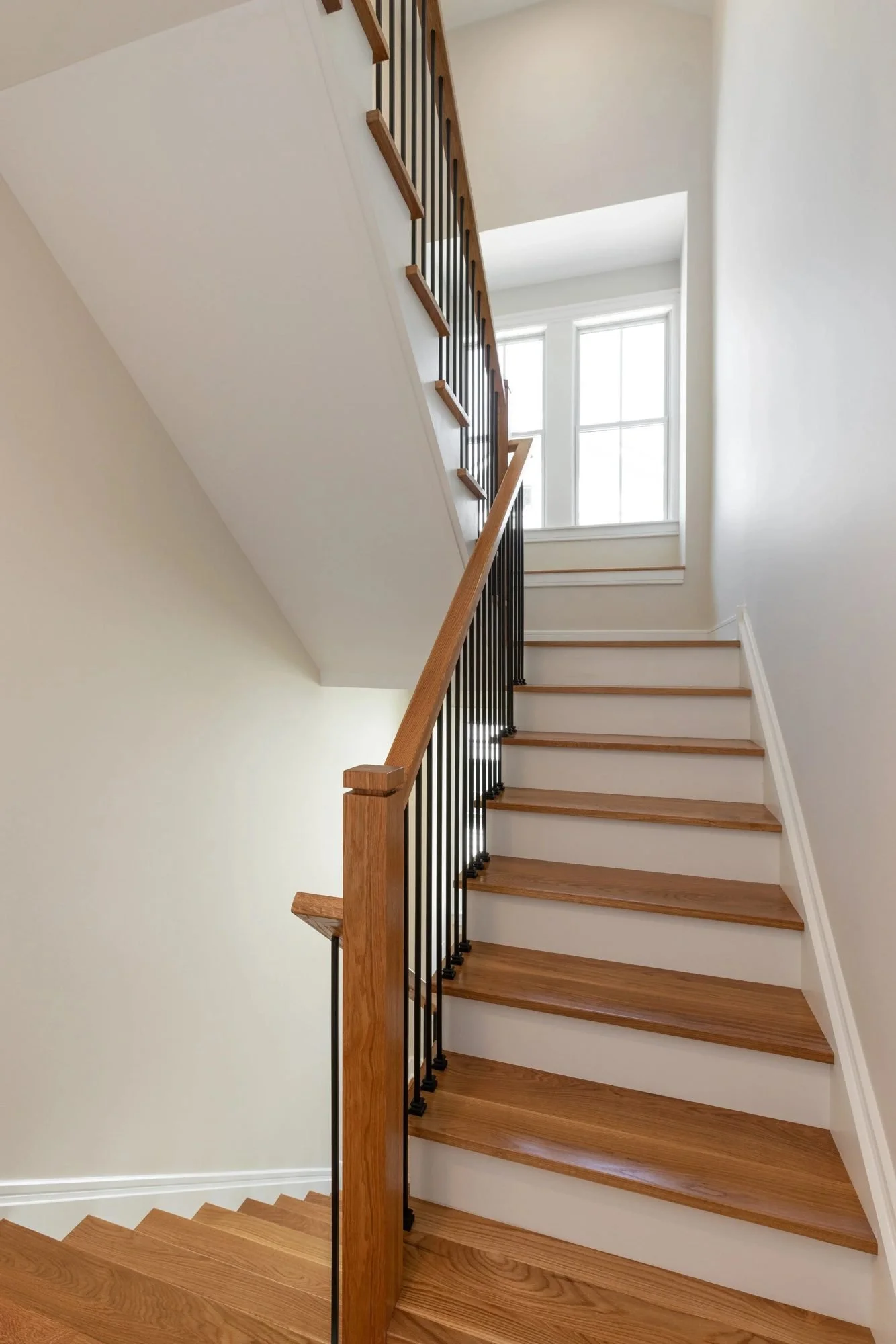 Staircase with white risers, oak treads and iron balusters