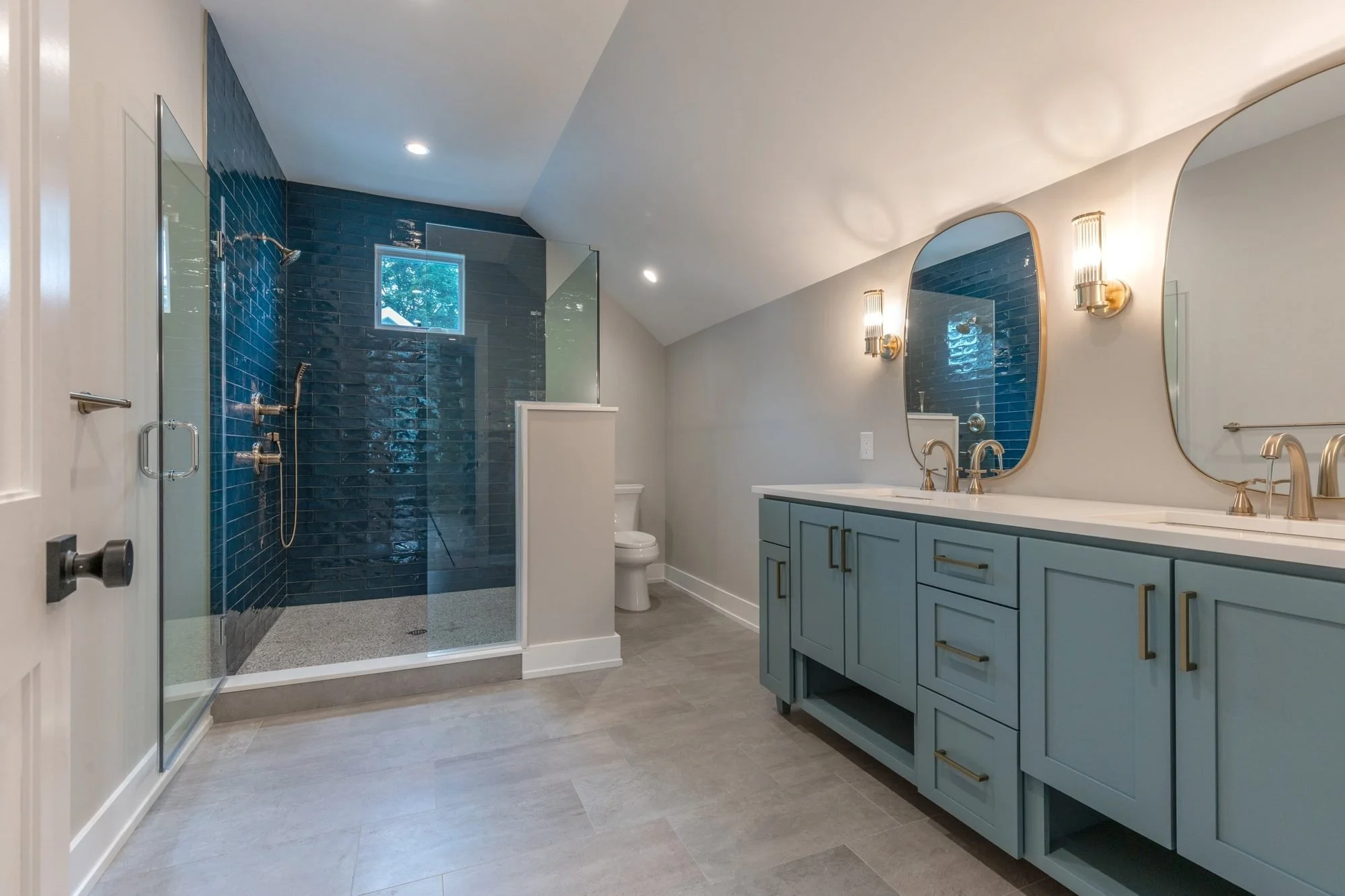 Bathroom with teal vanity and blue glass tile shower