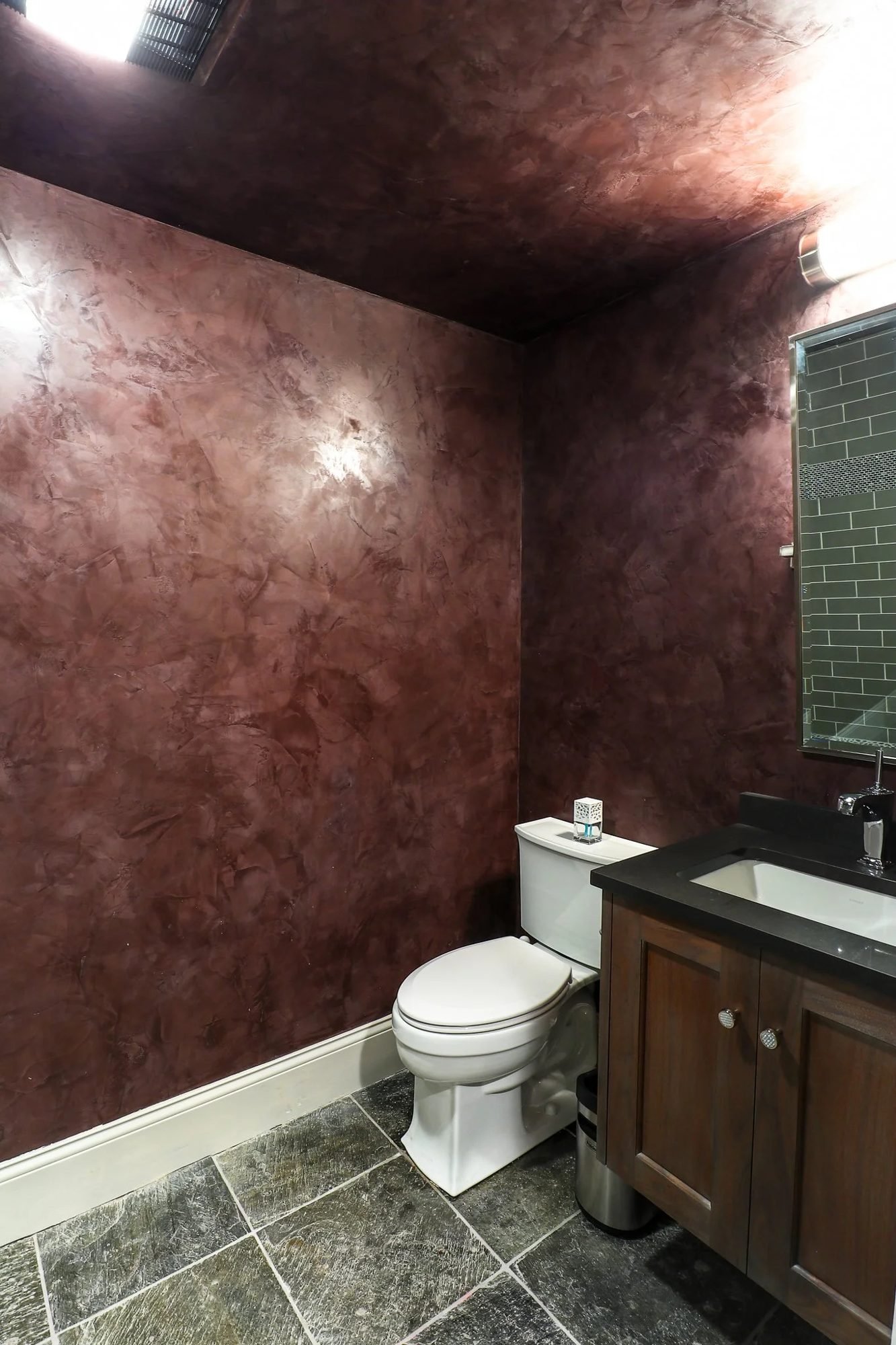 Bathroom with red Venetian plaster walls and dark wood vanity