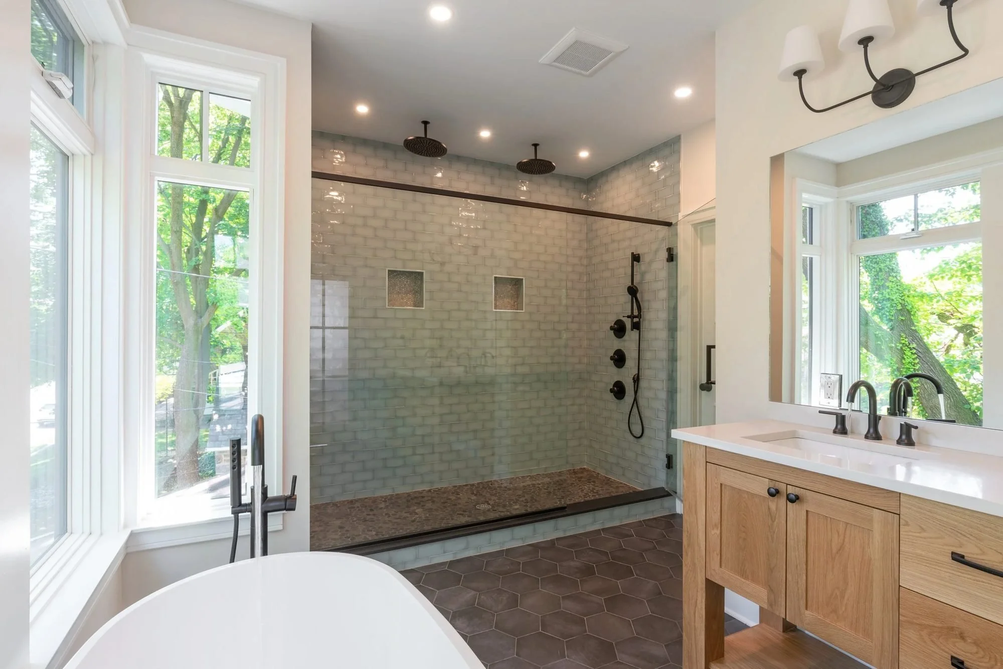Walk-in shower with green glass subway tile and matte black fixtures
