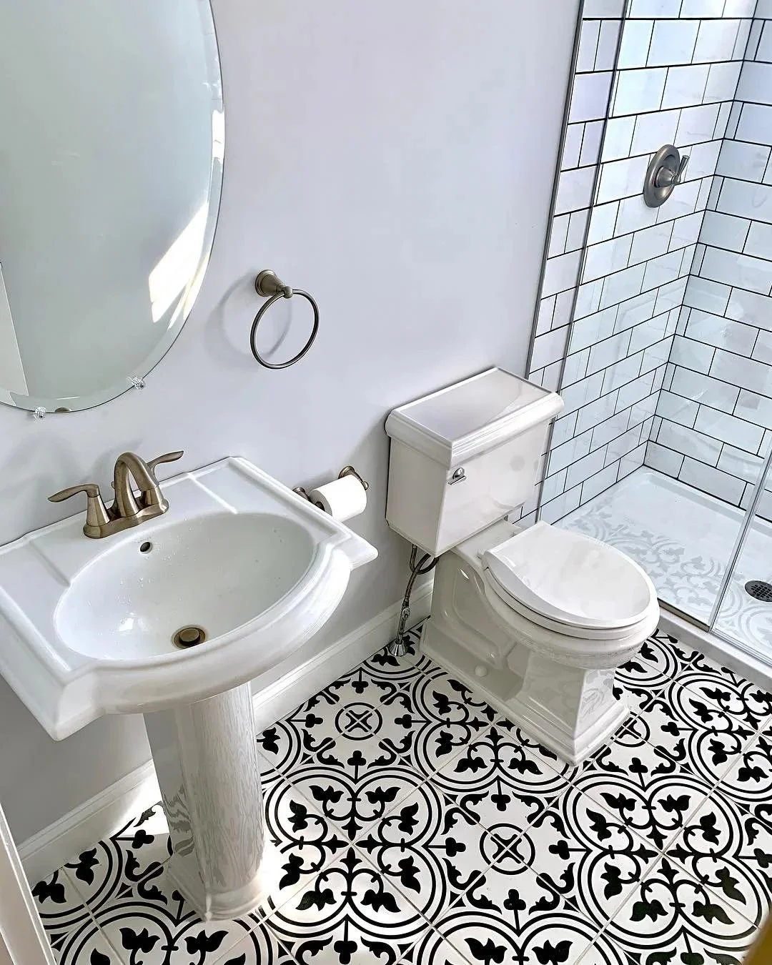 Pedestal sink and toilet on black-and-white patterned tile