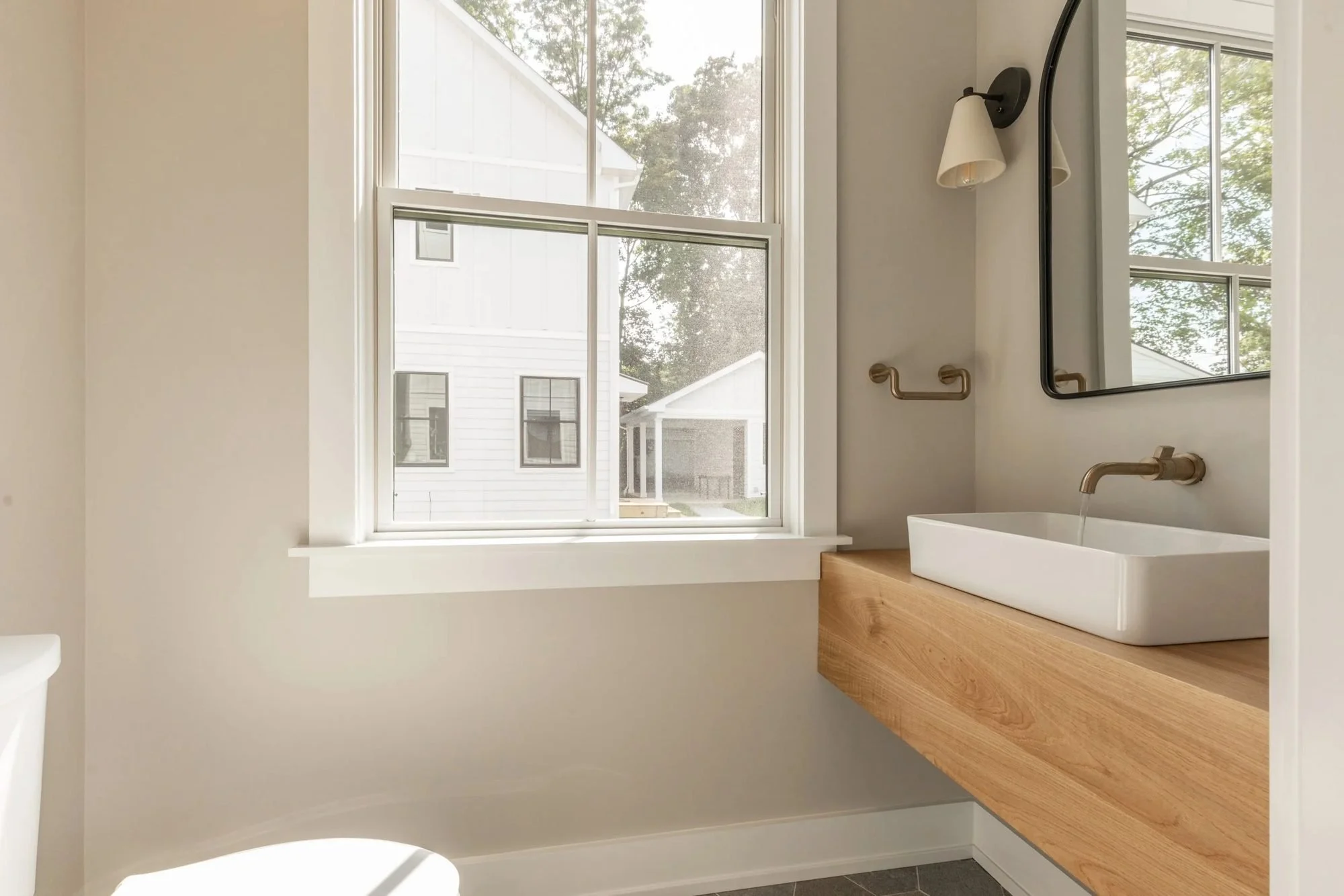 Powder room with floating oak vanity, vessel sink and wall-mount faucet