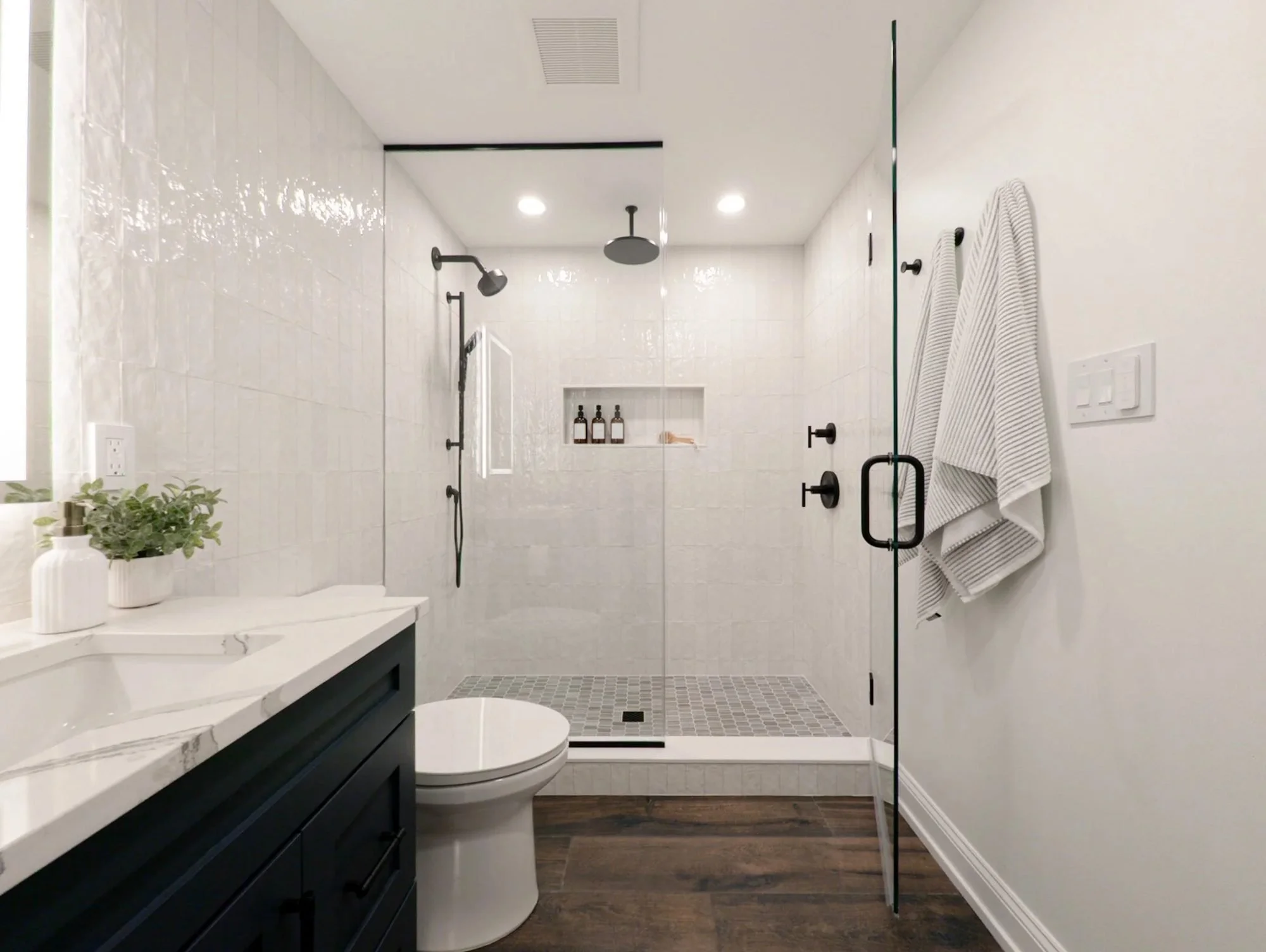 Basement bathroom walk-in shower with white tile and glass door
