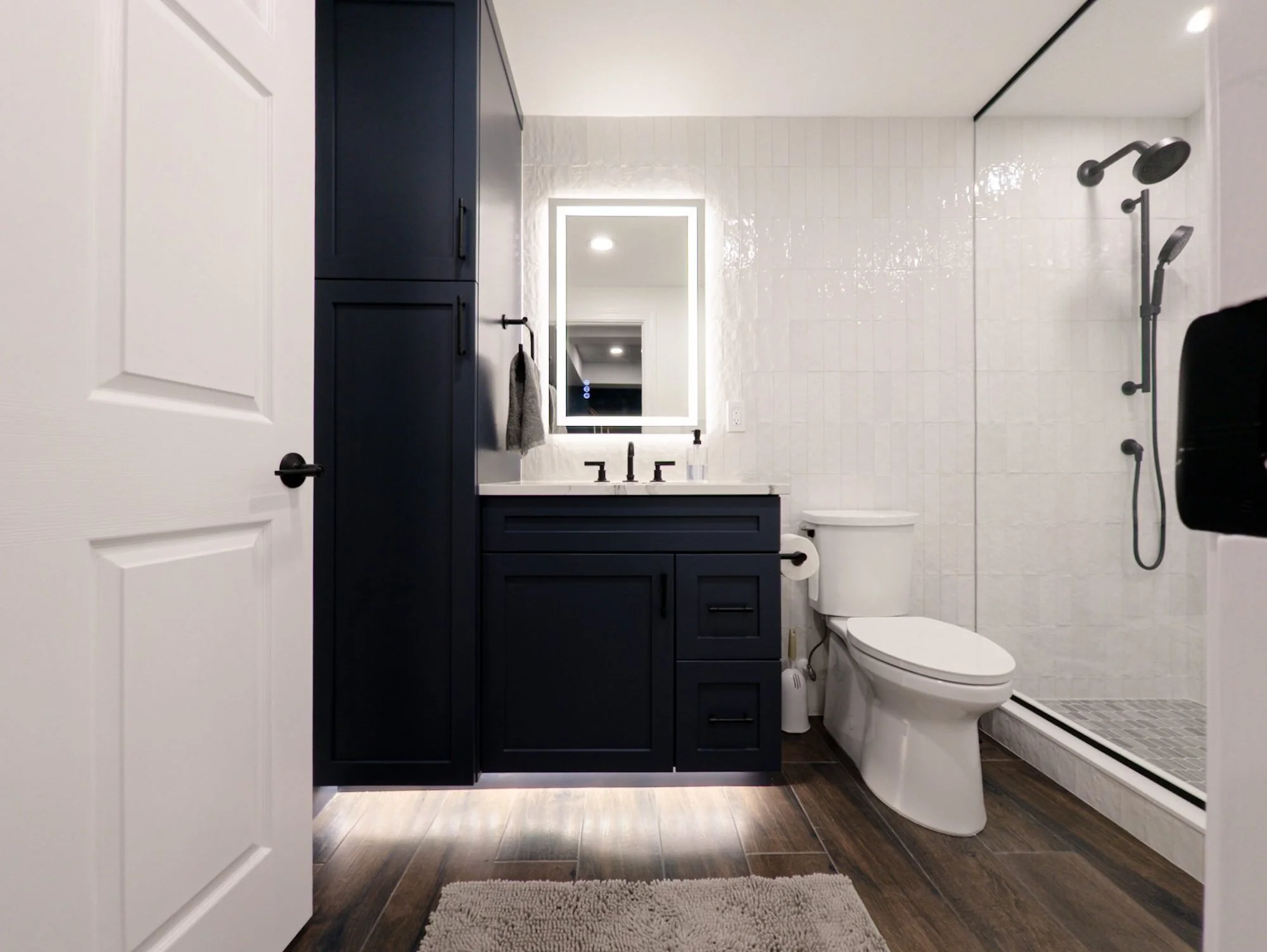 Basement bathroom with navy vanity, LED mirror and walk-in shower