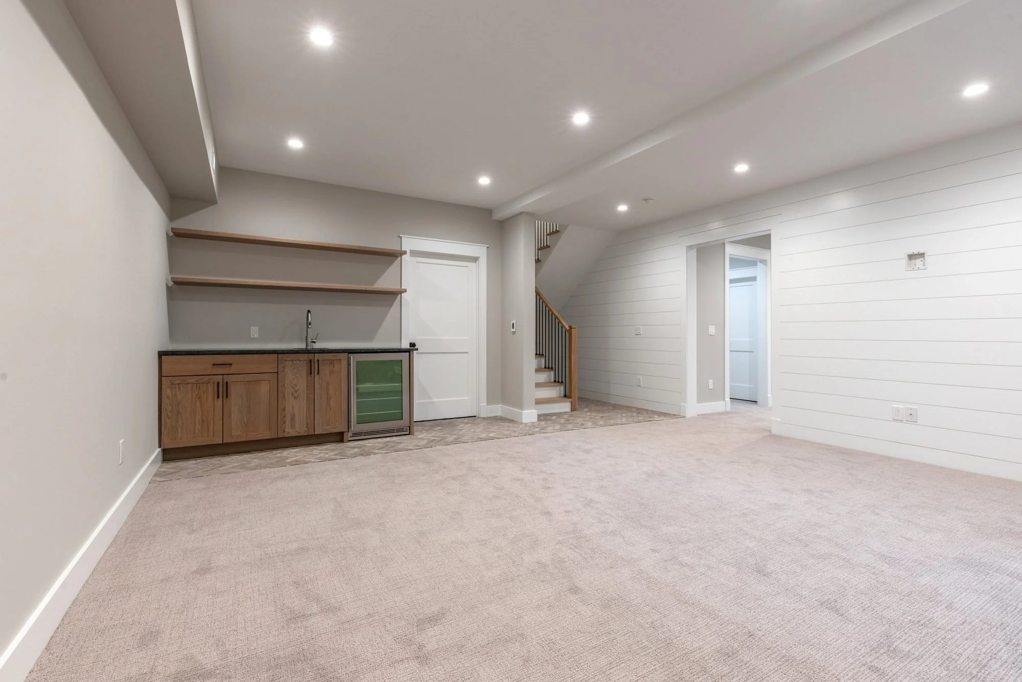 Finished basement with wet bar, floating shelves and shiplap wall