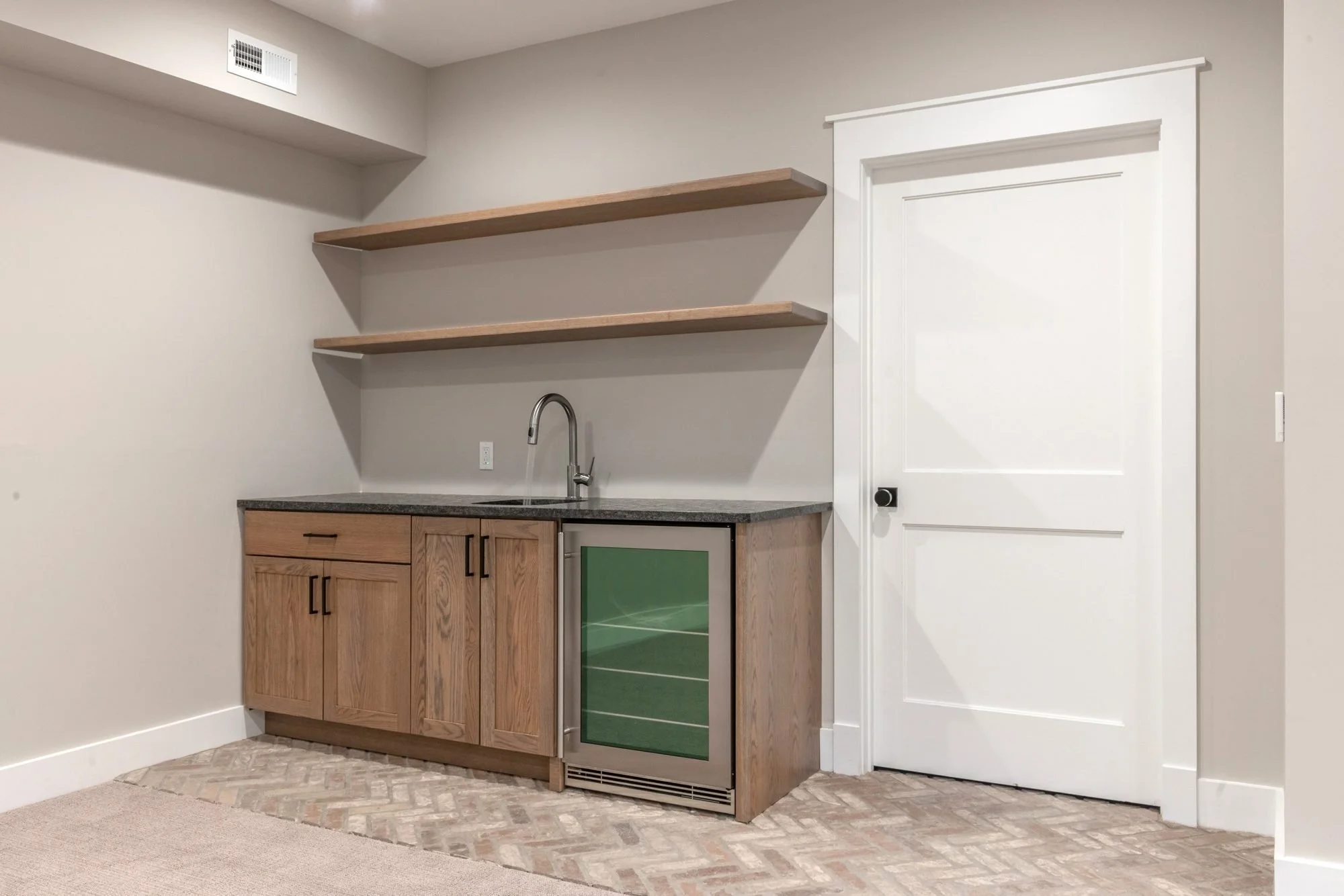 Basement kitchenette with wood cabinets, beverage fridge and floating shelves