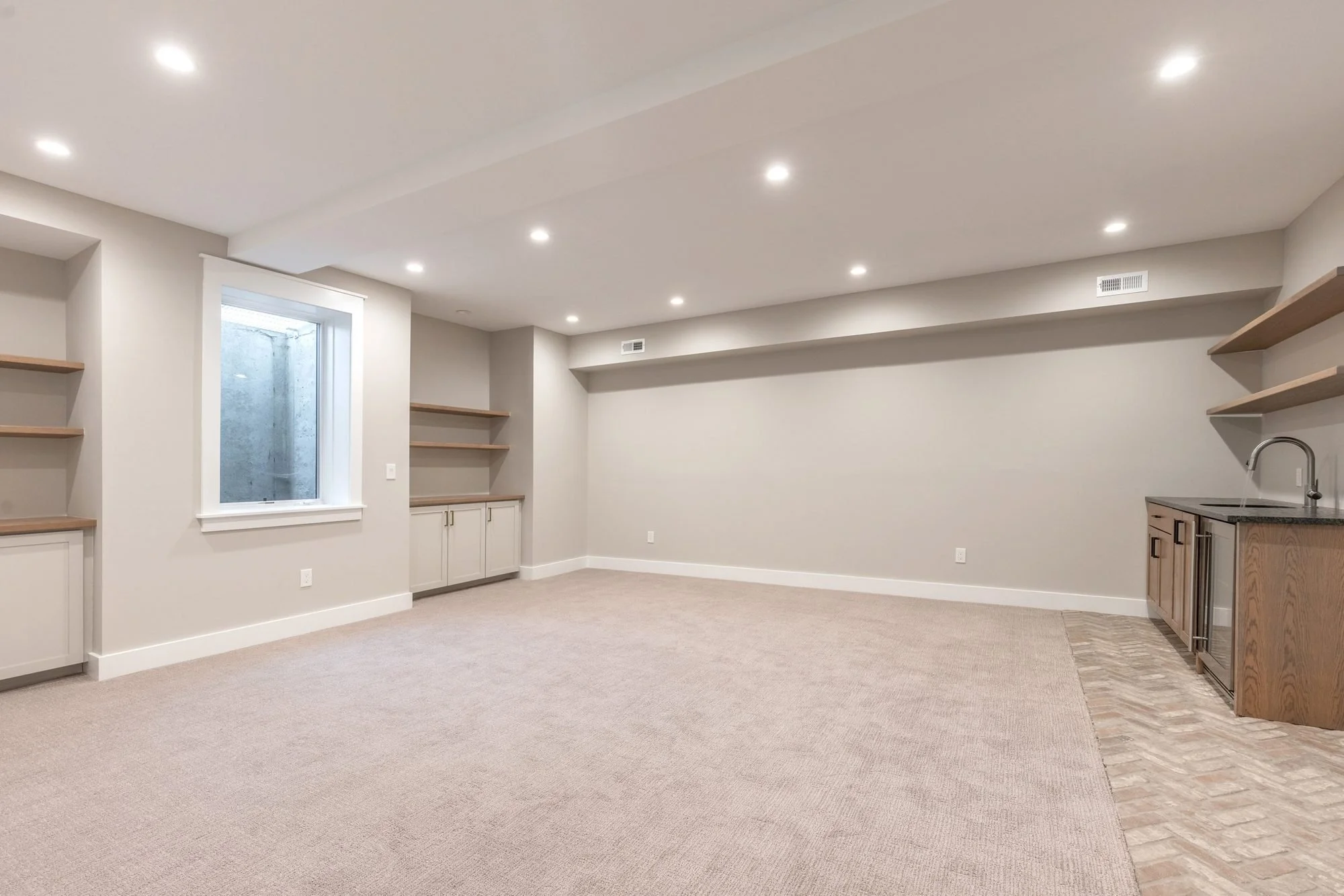 Finished basement rec room with built-in shelves and wet bar