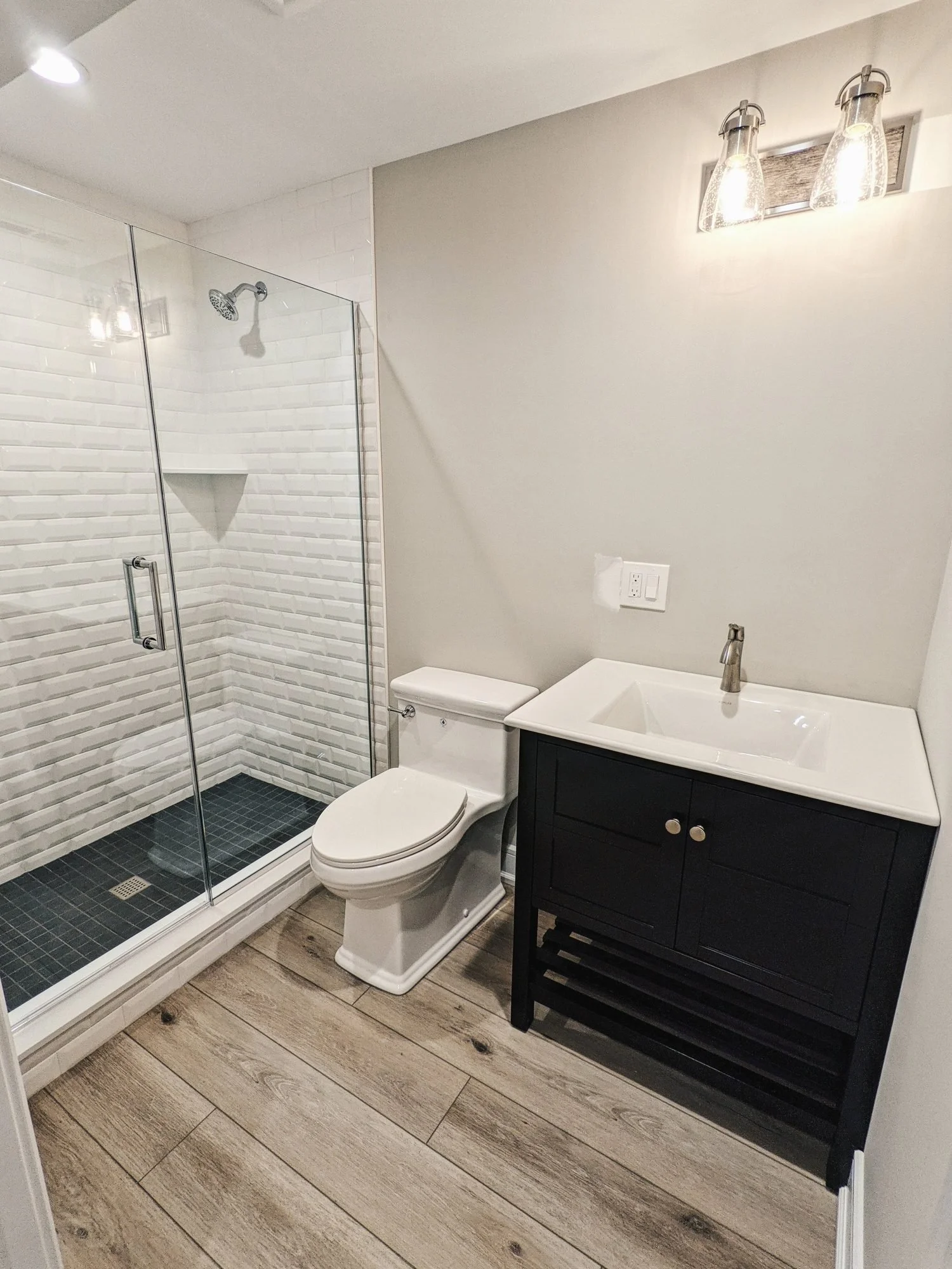 Basement bathroom with subway tile shower and black vanity