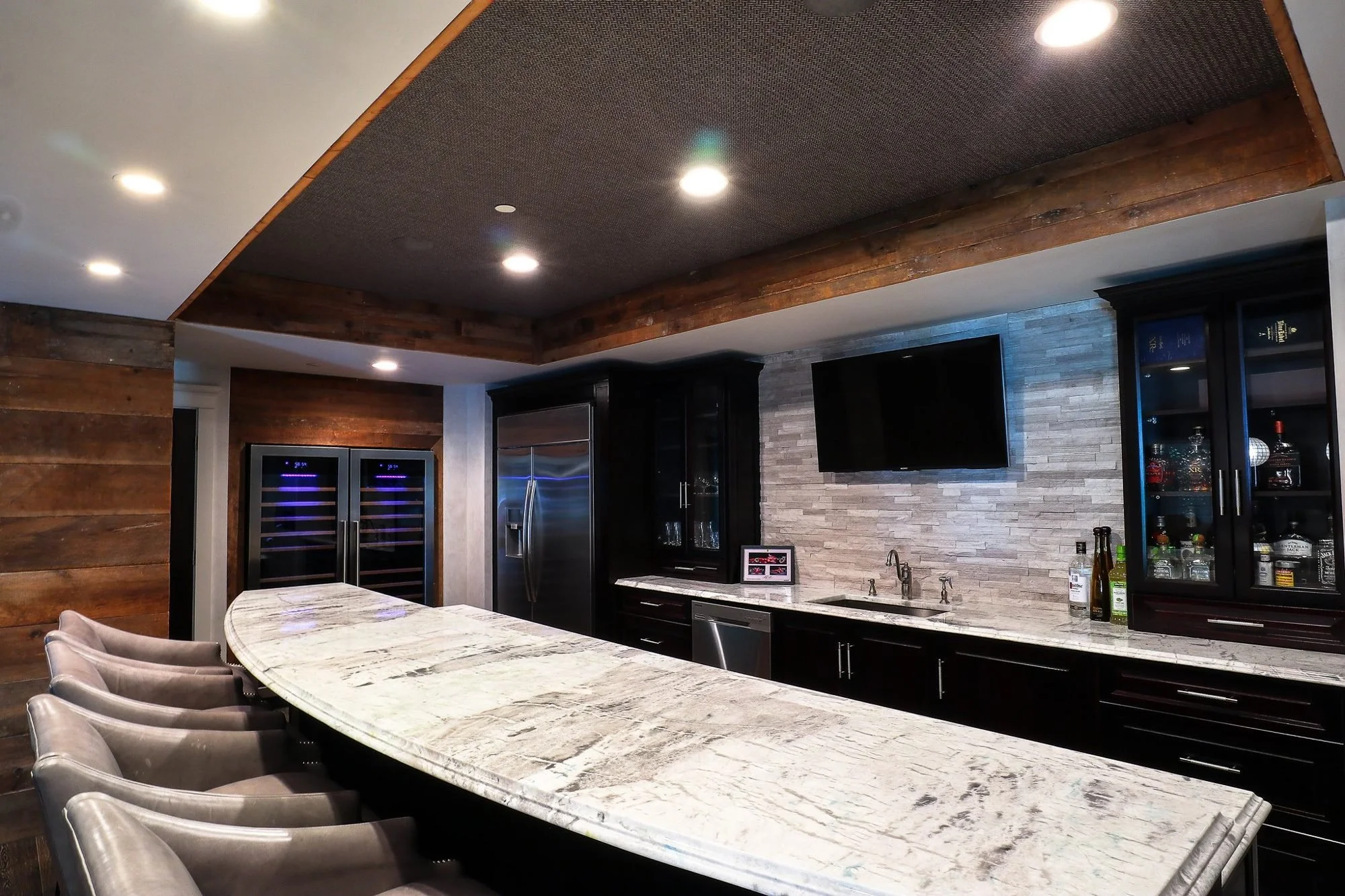 Luxury basement bar with curved marble counter and reclaimed wood walls