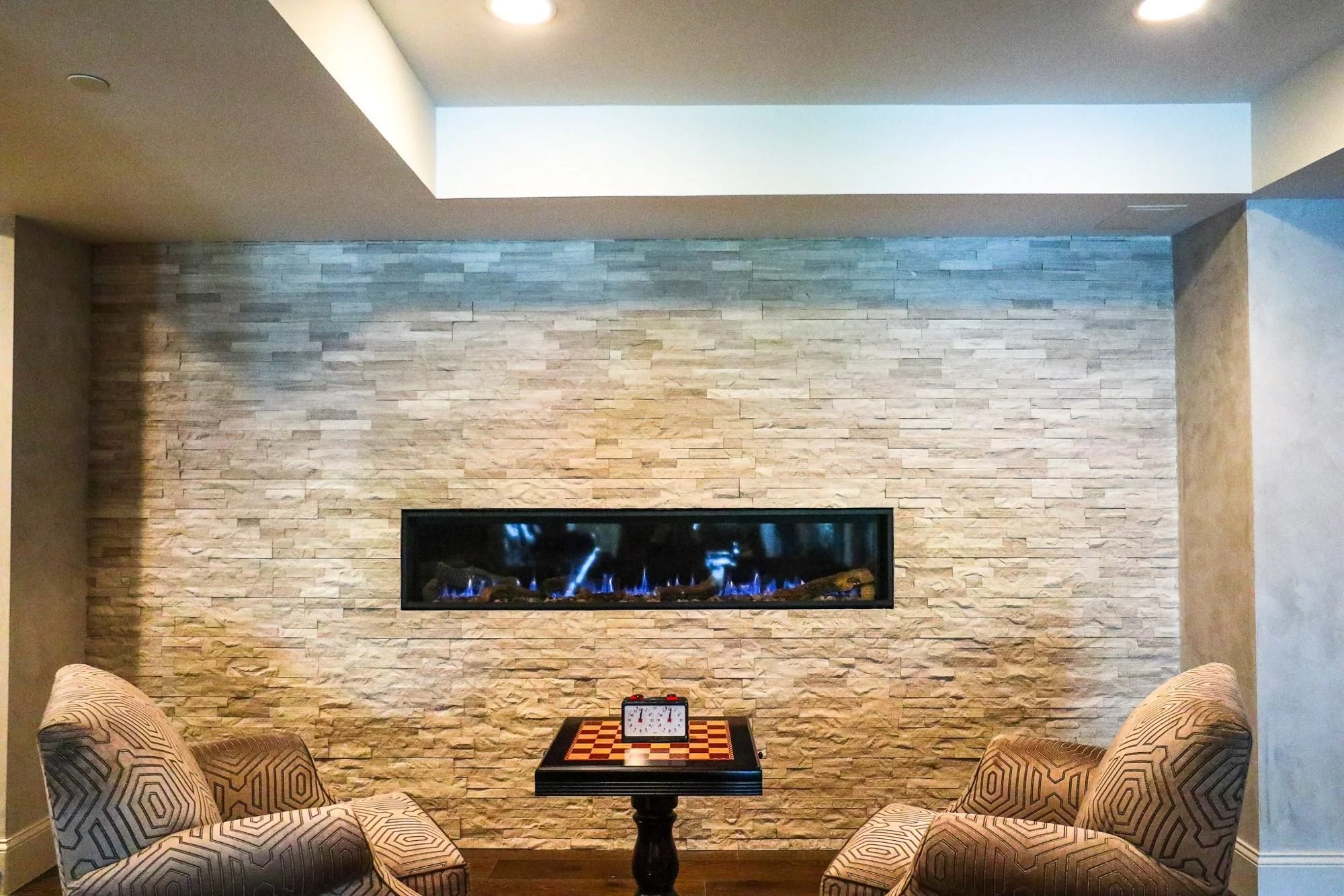 Stacked stone wall with linear gas fireplace in a finished basement