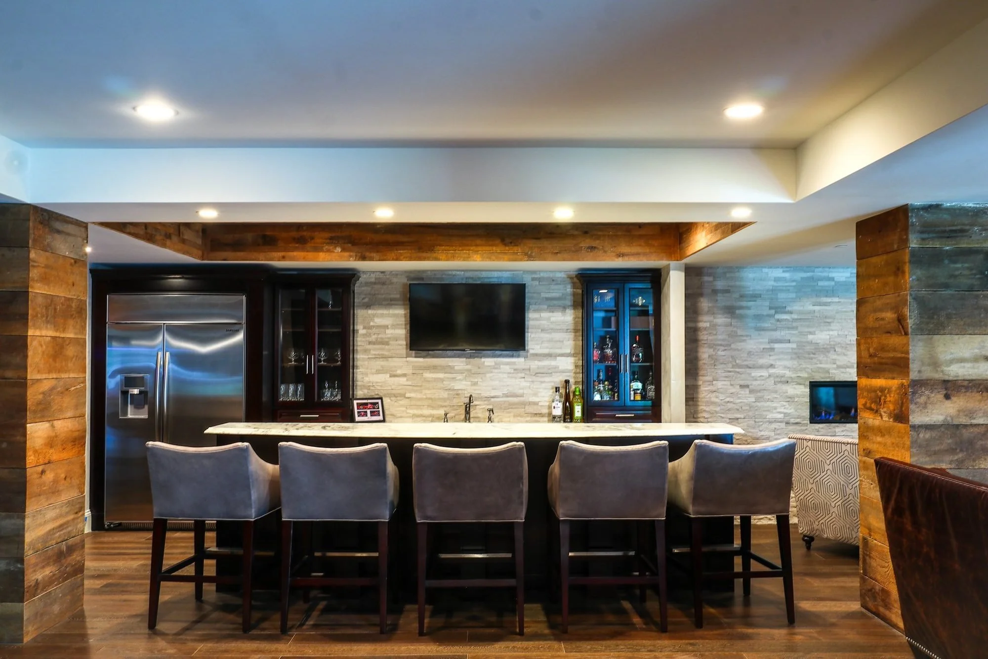 Basement bar seating with reclaimed wood columns and stone backsplash