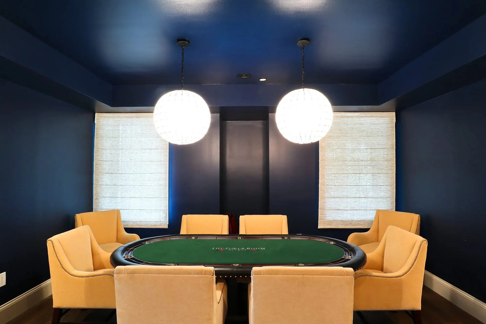 Basement game room with poker table, globe pendants and navy walls
