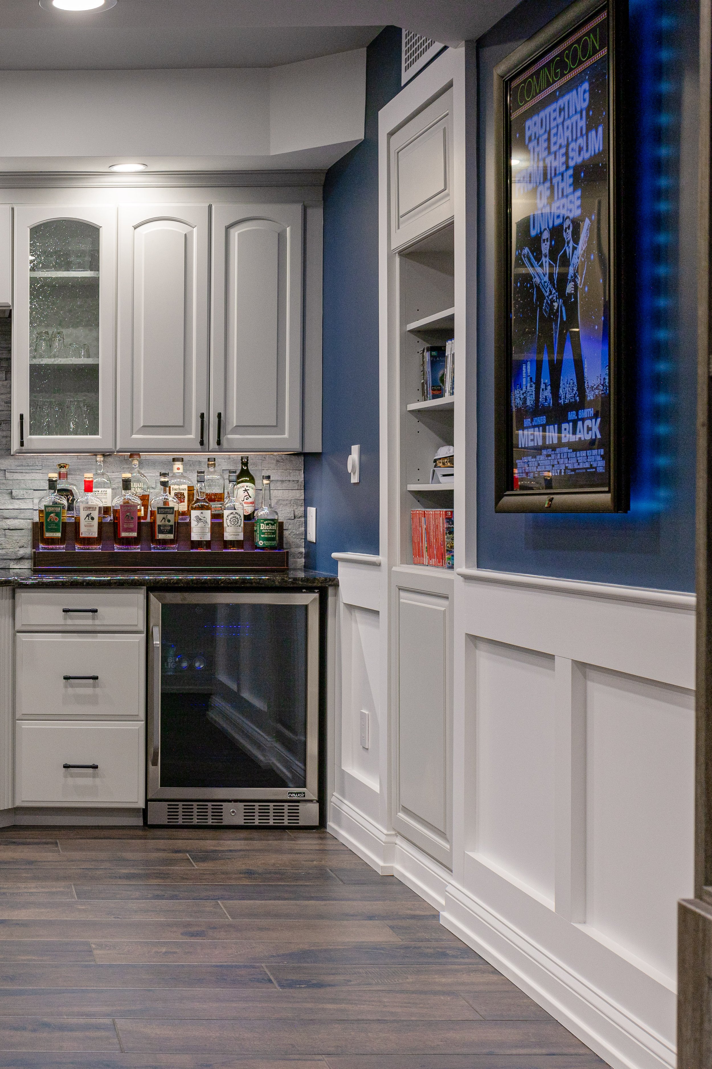 Custom basement bar with built-in cabinetry, beverage fridge, stone backsplash, and wainscoting detail in a Bucks County, PA home by Revival Building Group