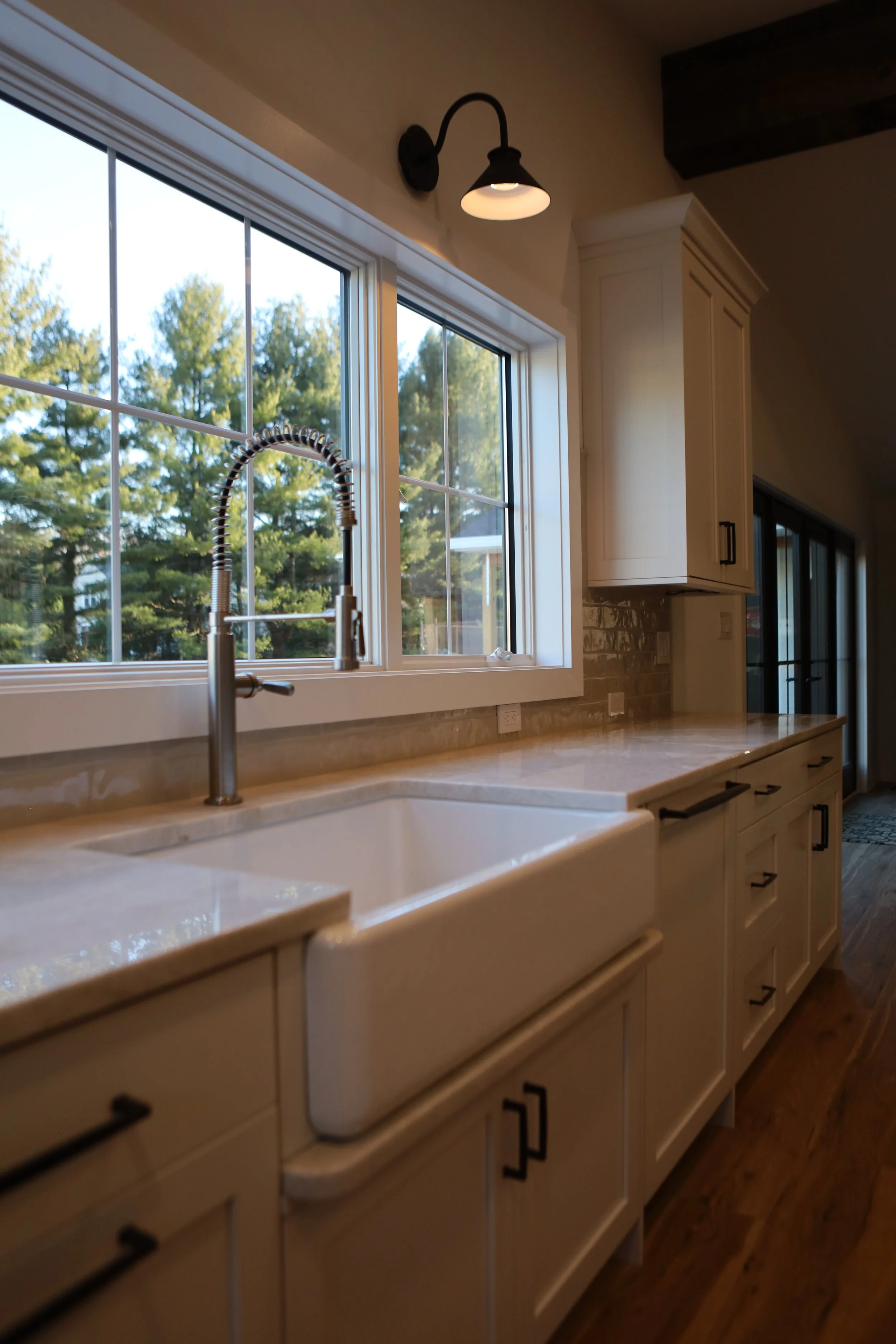 Custom kitchen with apron-front sink, white cabinetry, quartz countertops, and large windows bringing in natural light.