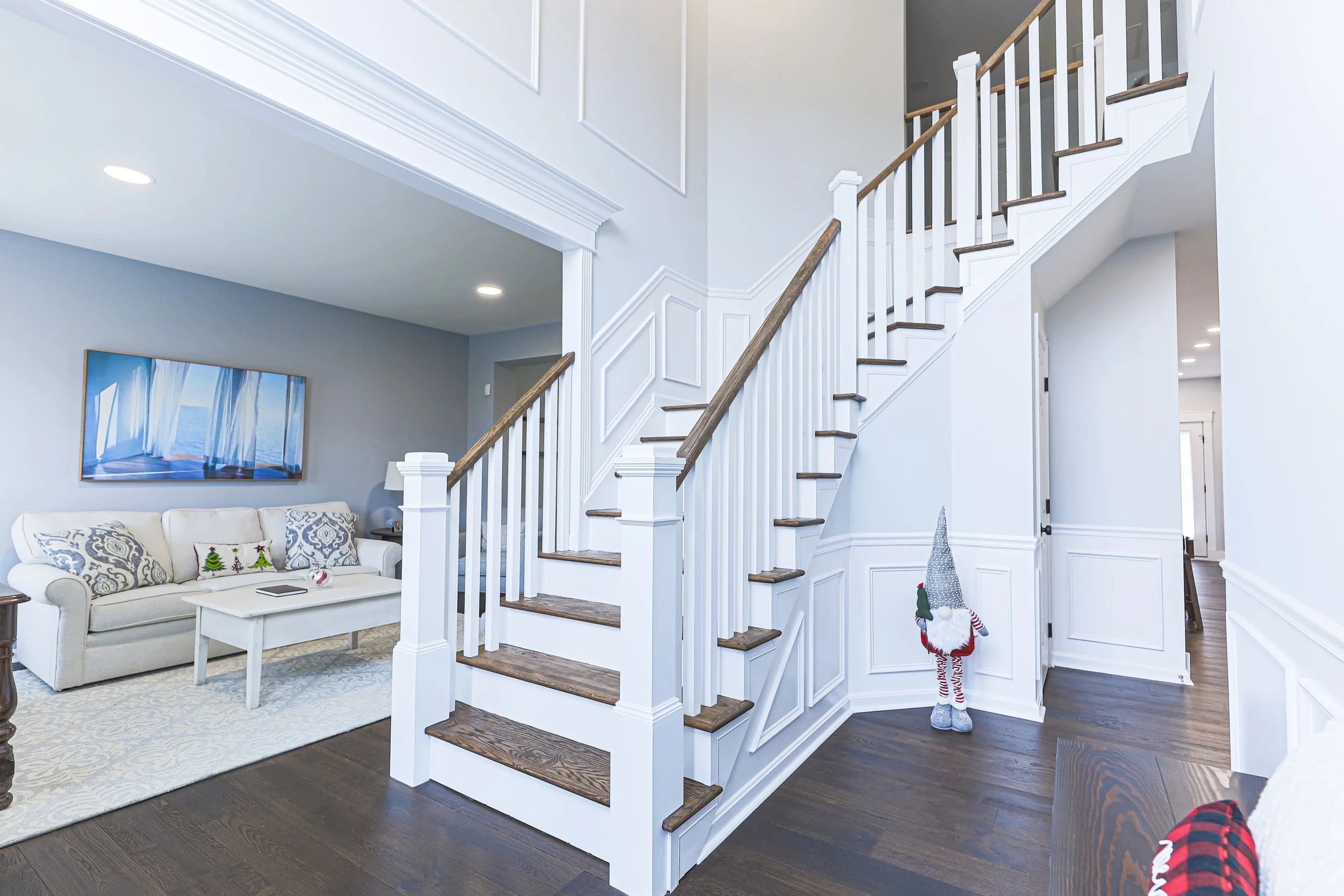 Entry foyer with white staircase and wainscoting opening to the living room
