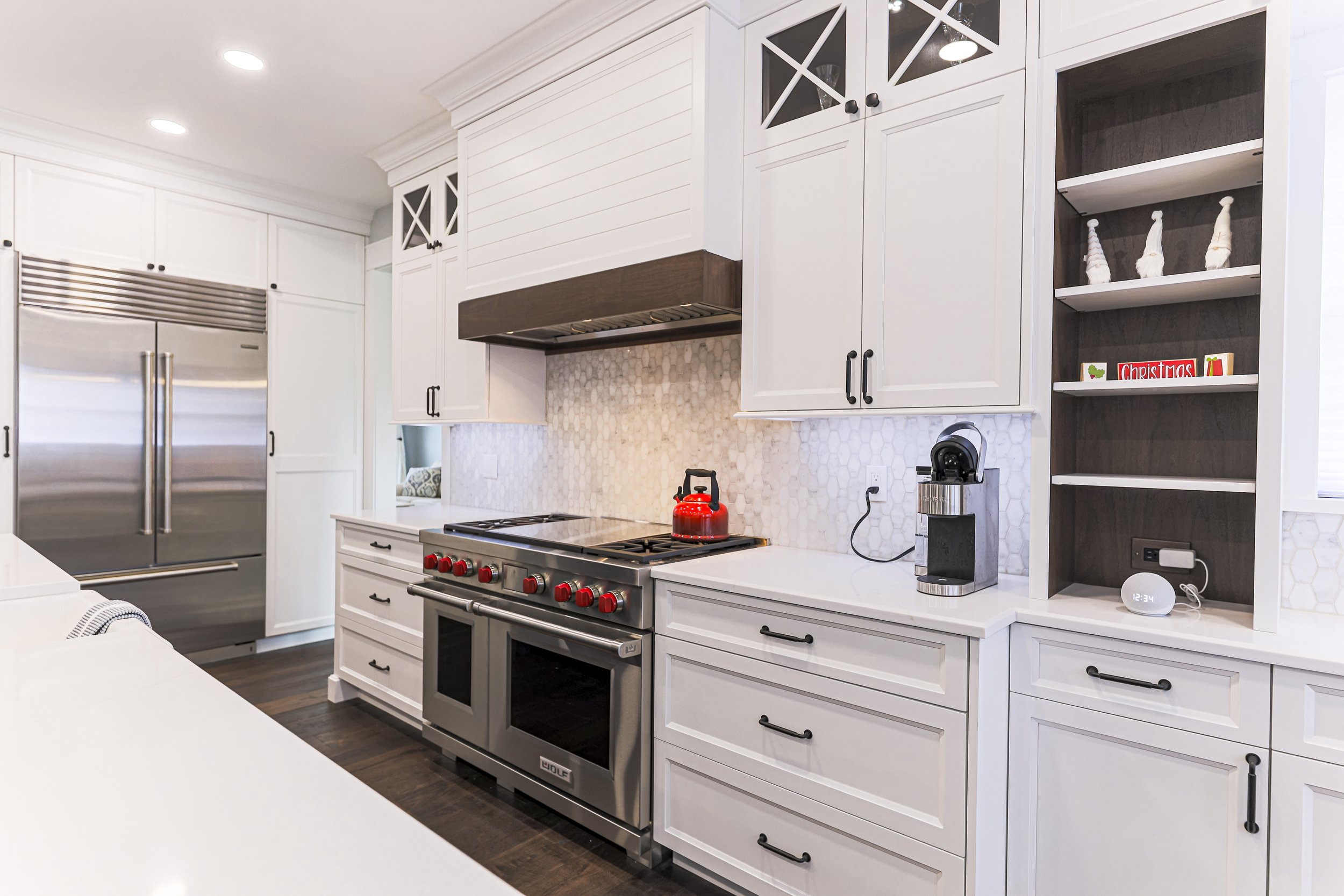 Professional range under a wood-trimmed hood with built-in refrigerator and open shelving