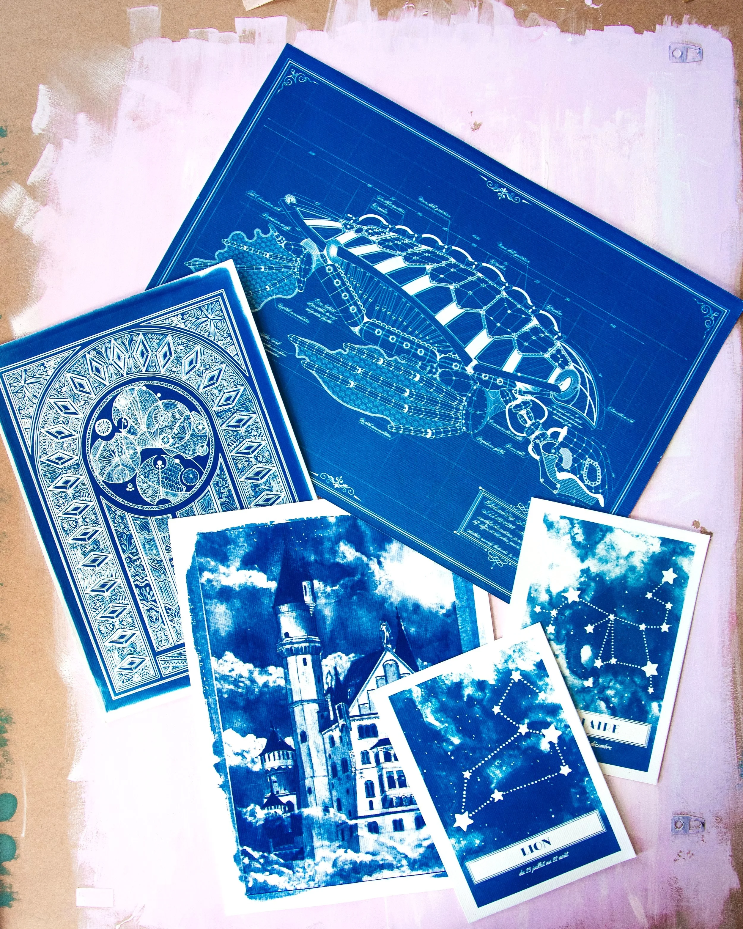 Des plans architecturaux bleus, une illustration d'une cathédrale, et des cartes de tarot avec des images de chats, de paysages et de constellations.