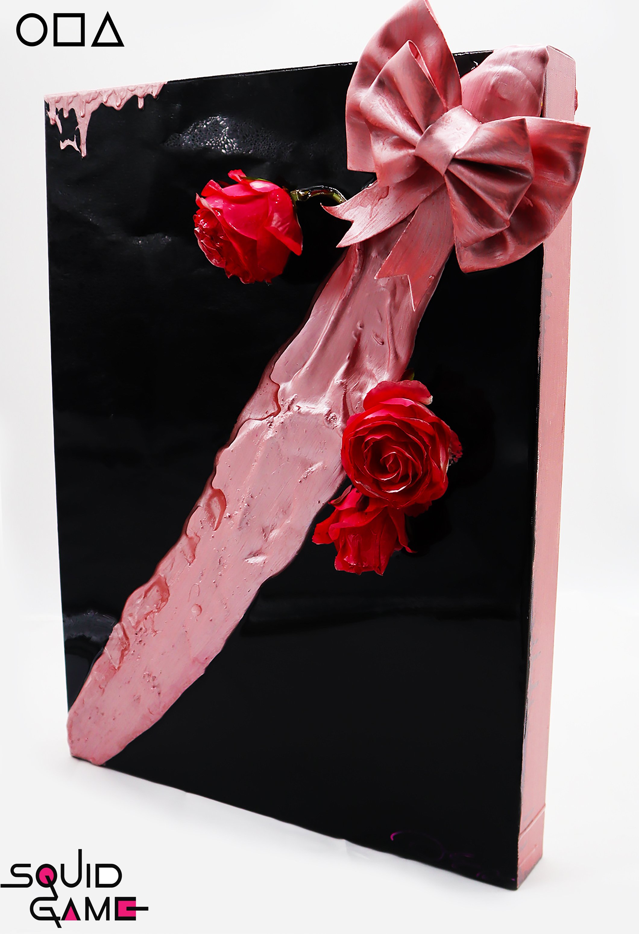 A mixed media art piece featuring a large pink finger with a bow on top, adorned with three red roses, against a black background with a faint logo in the upper left corner.