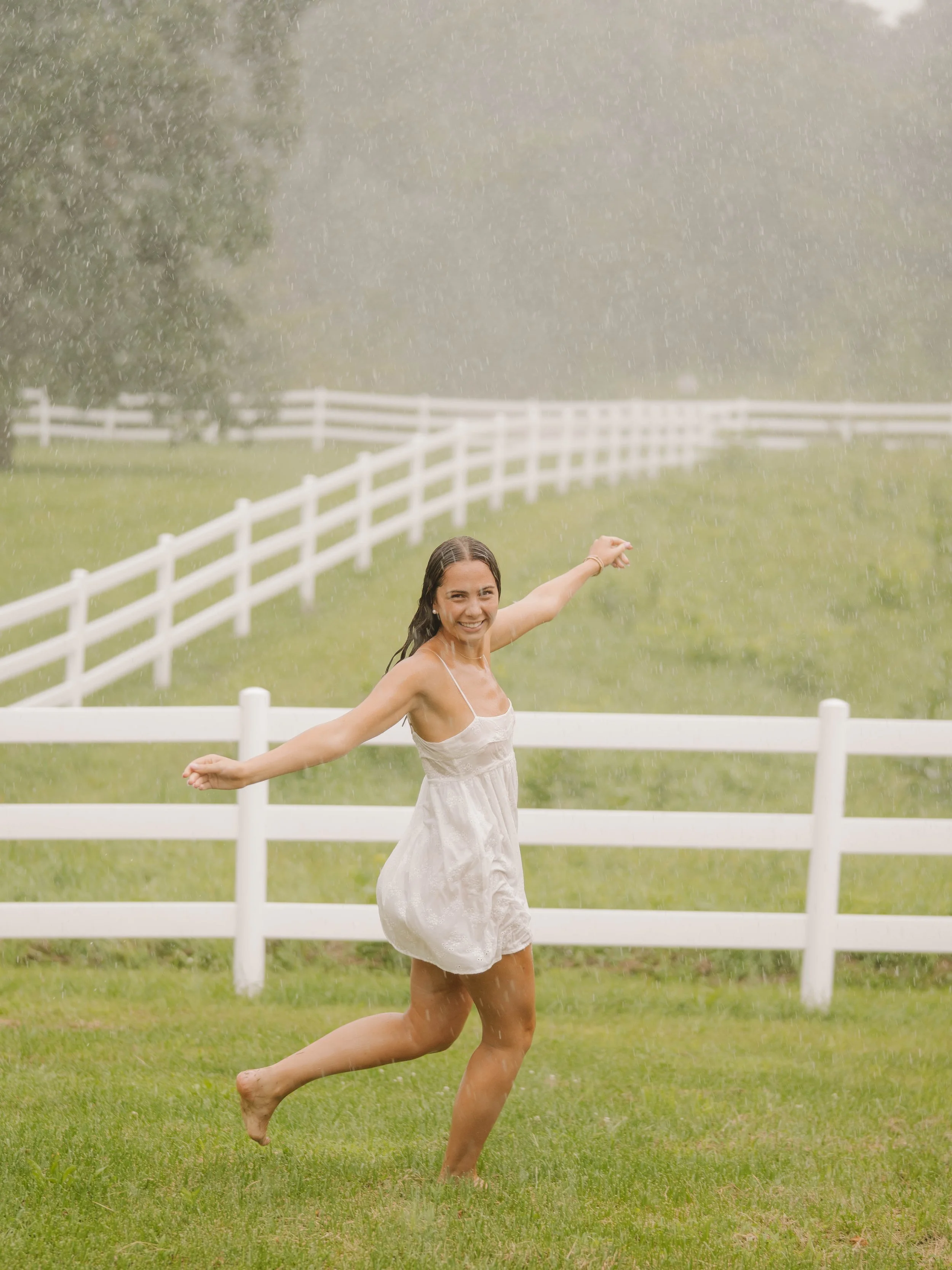Young person smiling by a sunlit lake, wearing a maroon Loyola University Chicago t-shirt and jeans.