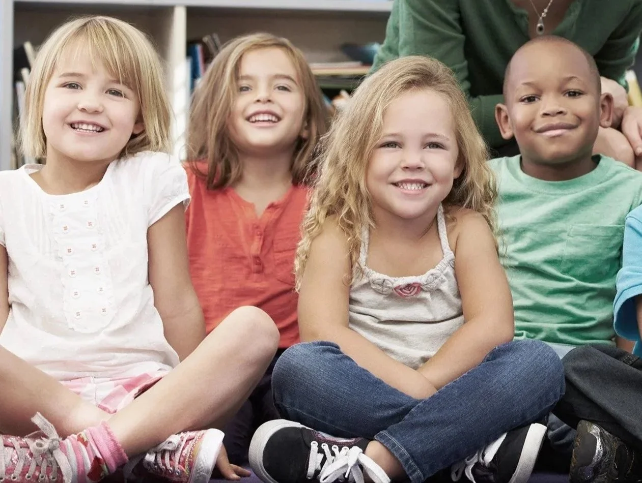 the hamper hub footer image of children sitting cross legged at school