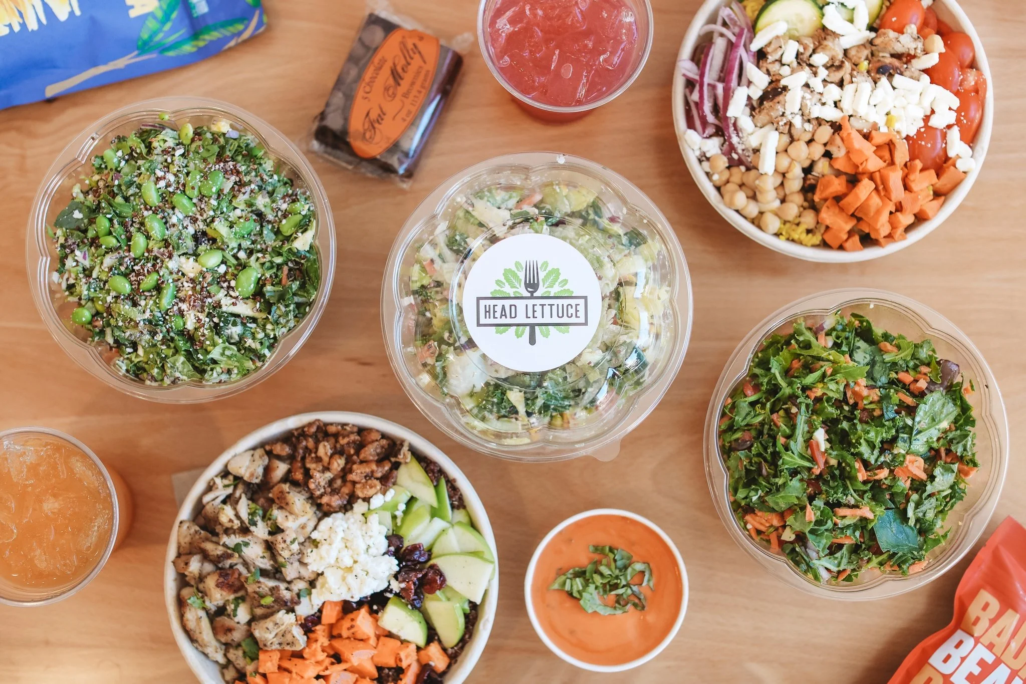 Table full of salads with lids off and soup