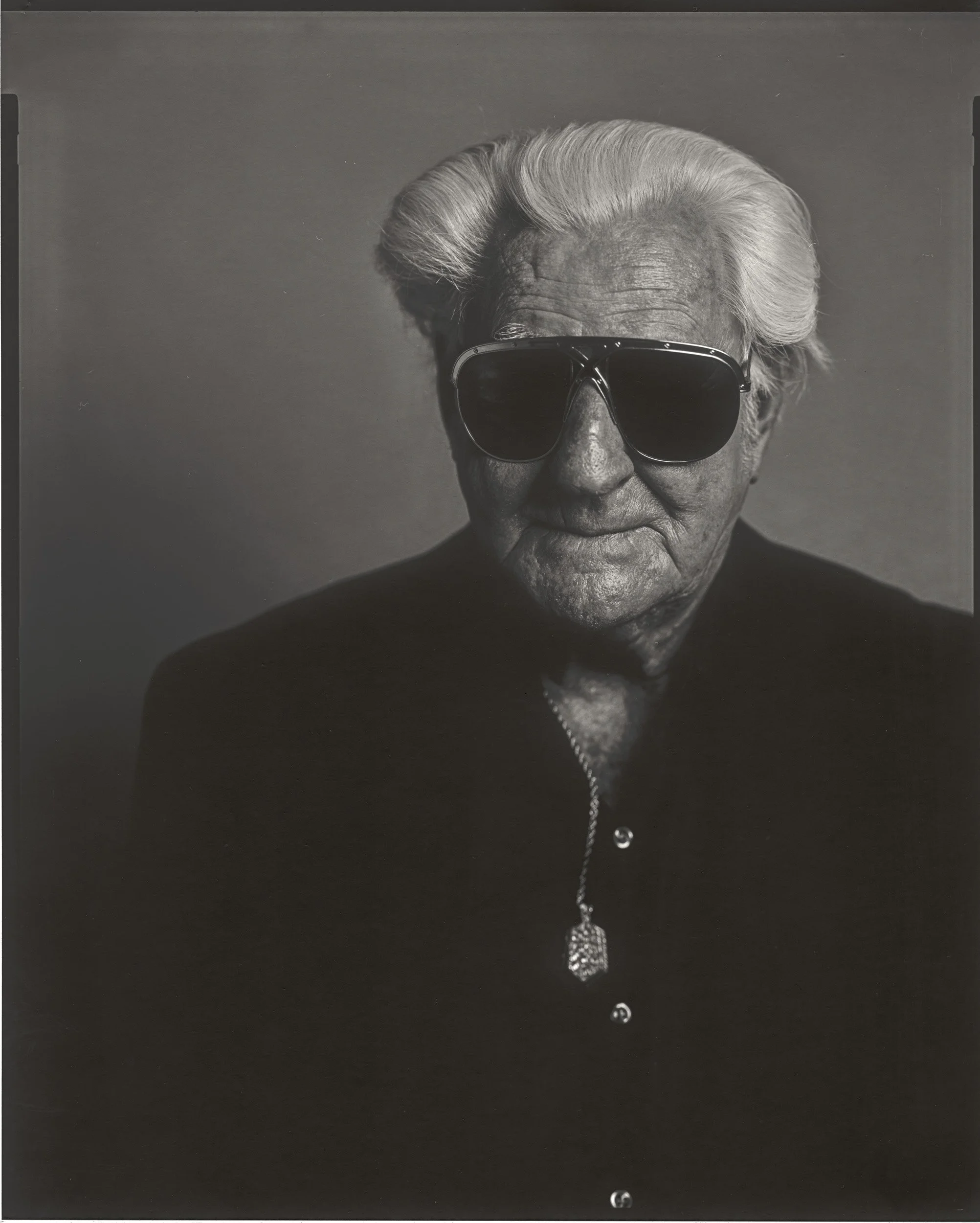 A striking black and white large format film portrait of an older musician in sunglasses and a black suit, capturing the spirit of Madison County bluegrass by Parker J Pfister