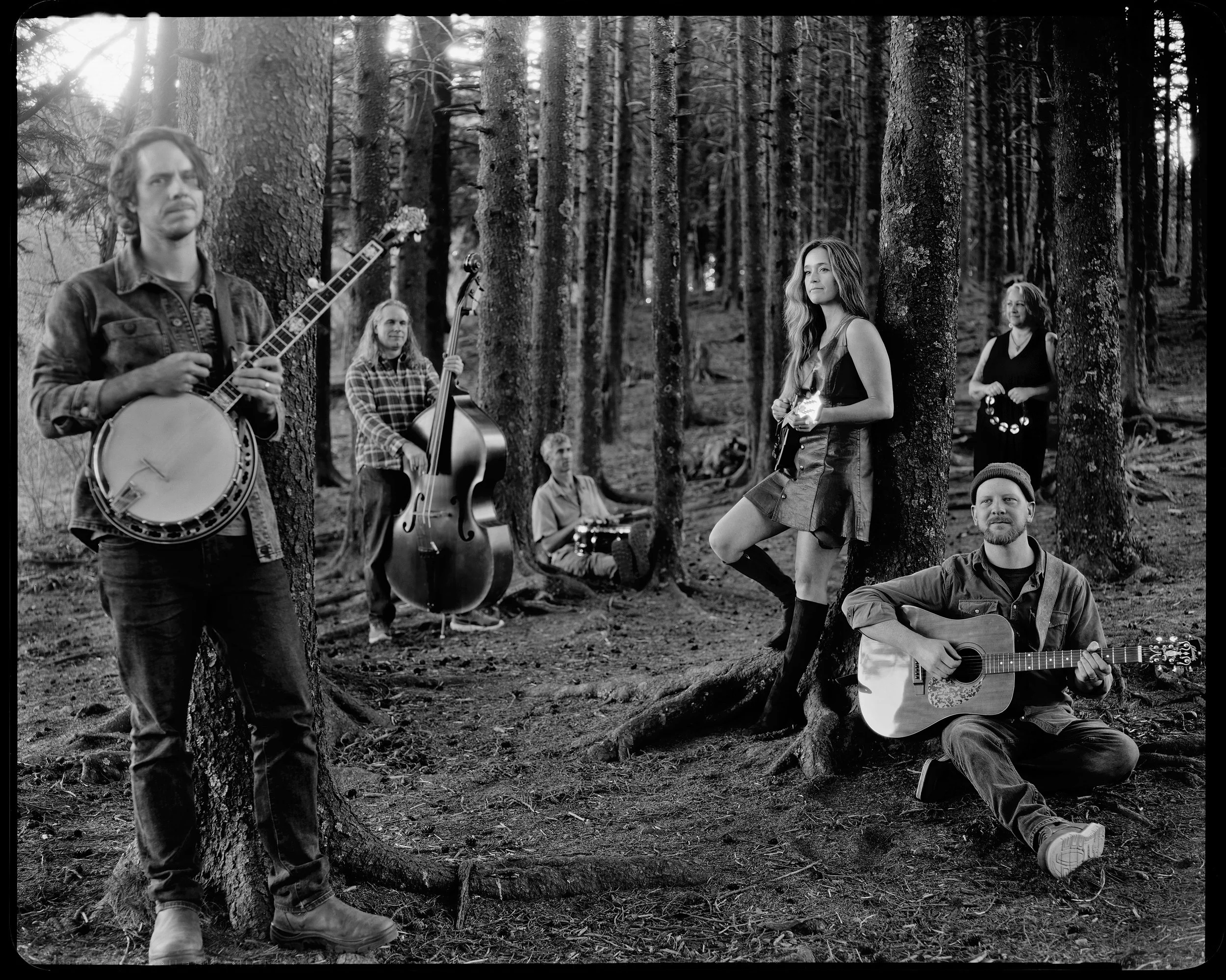 Black and white portrait of Western North Carolina band Blue Ridge Betty performing with banjo and guitar among pine trees, fine art 8x10 silver gelatin paper print by Parker J. Pfister.