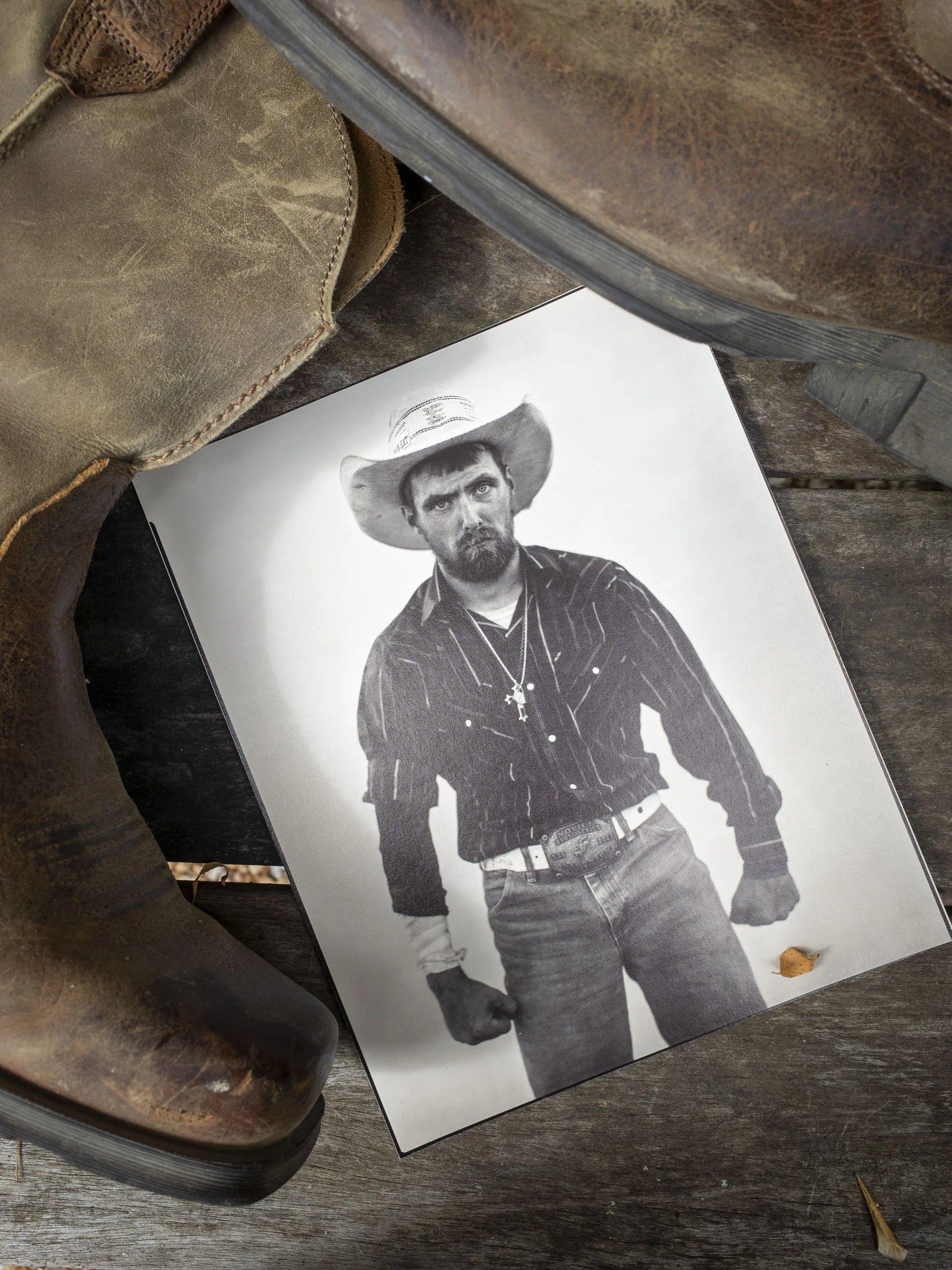 A photograph displaying a physical darkroom print of the large format Madison County rodeo portrait, showcasing the raw edges of the paper and the tangible quality of the photographic print.