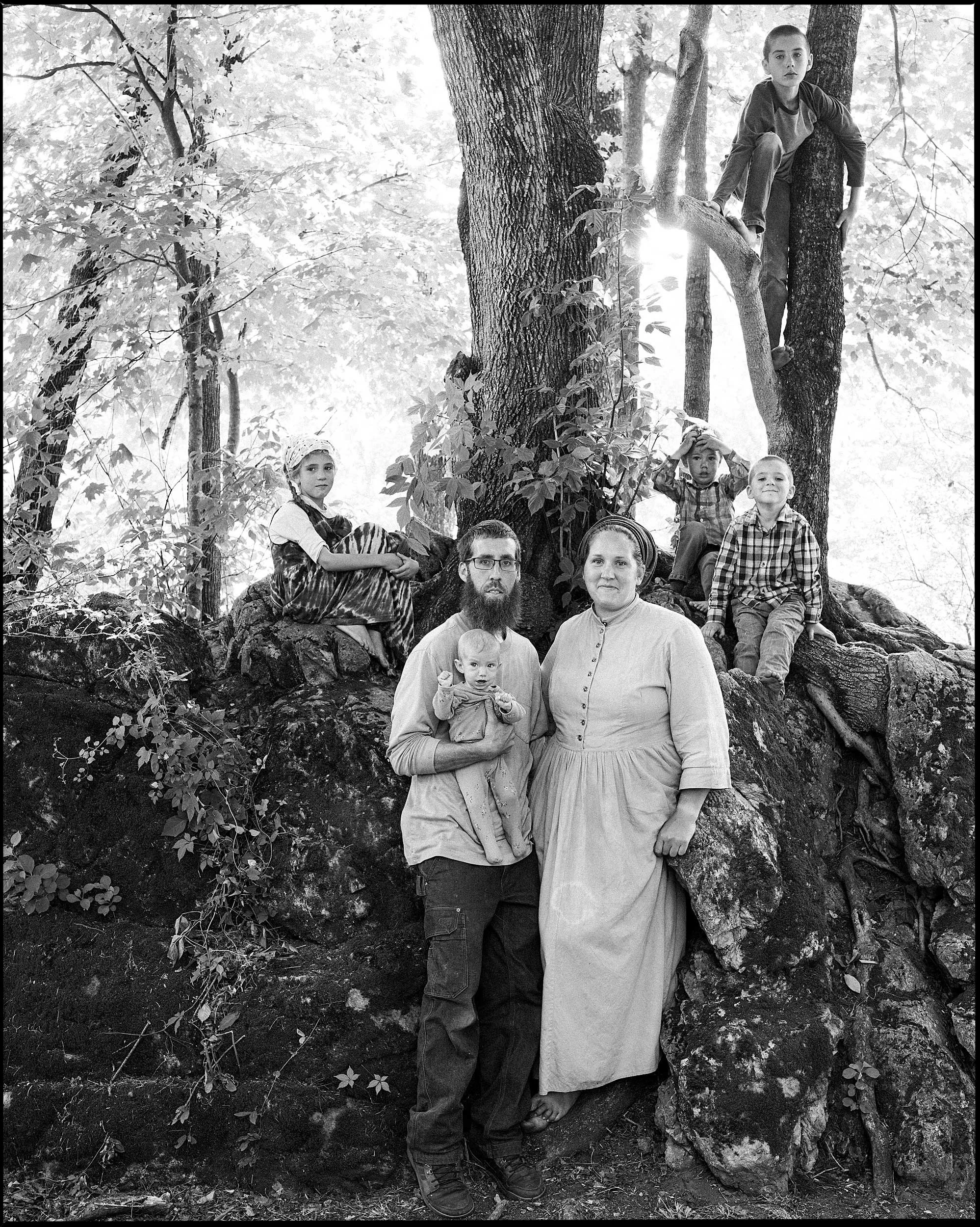 Black and white portrait of an Appalachian family sitting on a large rock in the woods of Hot Springs North Carolina by Parker J Pfister