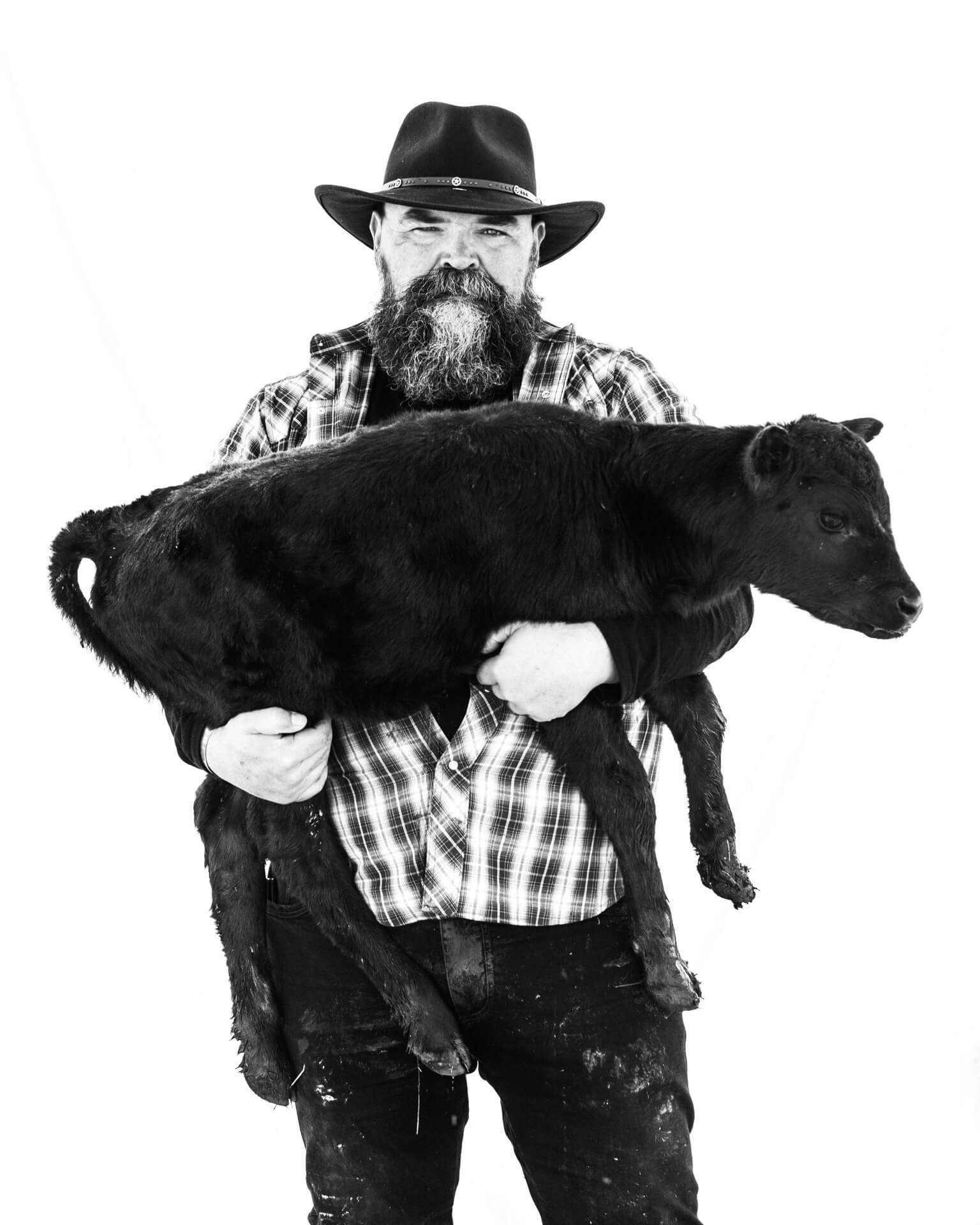 Self Portriat of Parker J Pfister in black and white holding a calf.