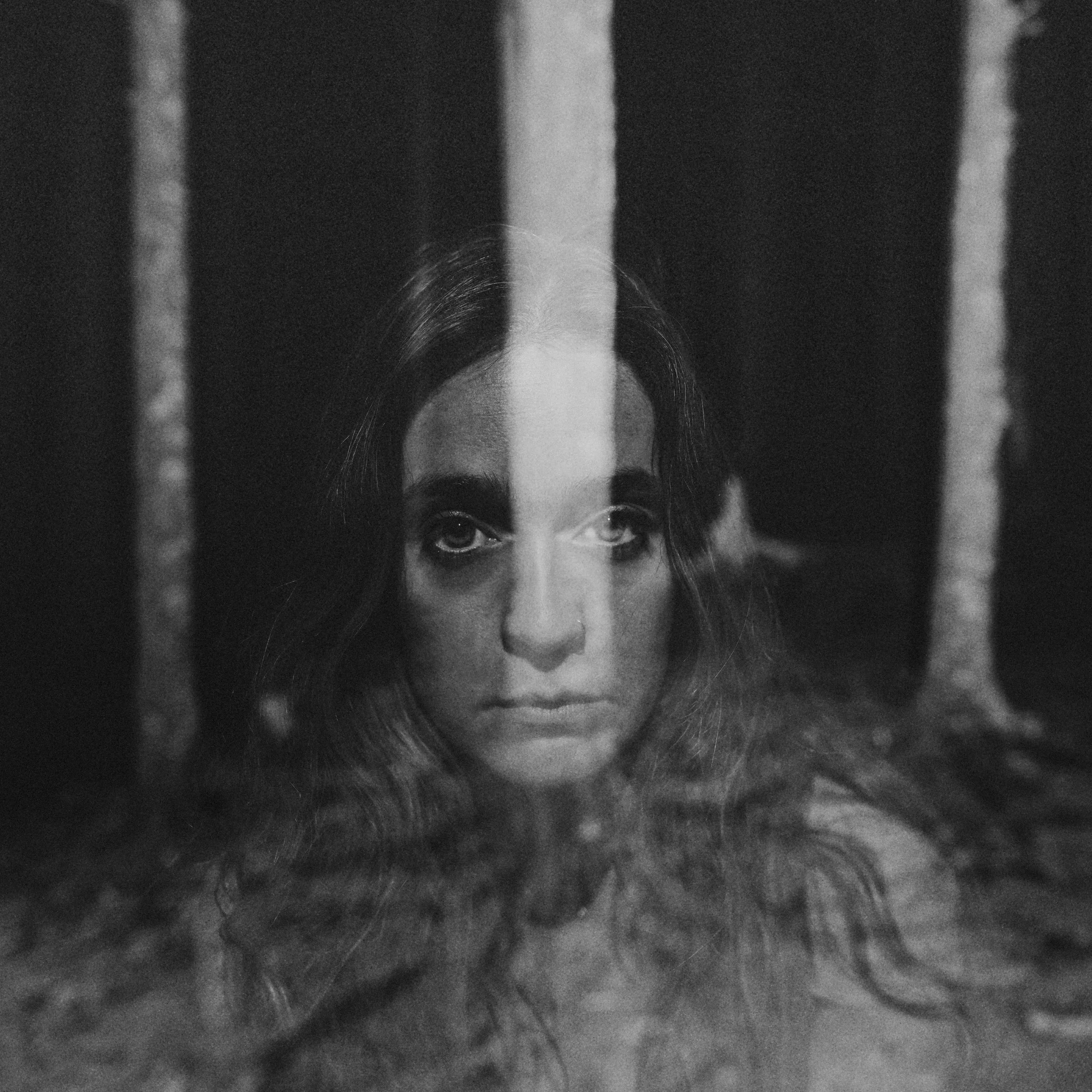 Haunting black and white portrait of singer-songwriter Lindsey Wall double exposure with ghostly forest light reflections, photographed by Parker J. Pfister.