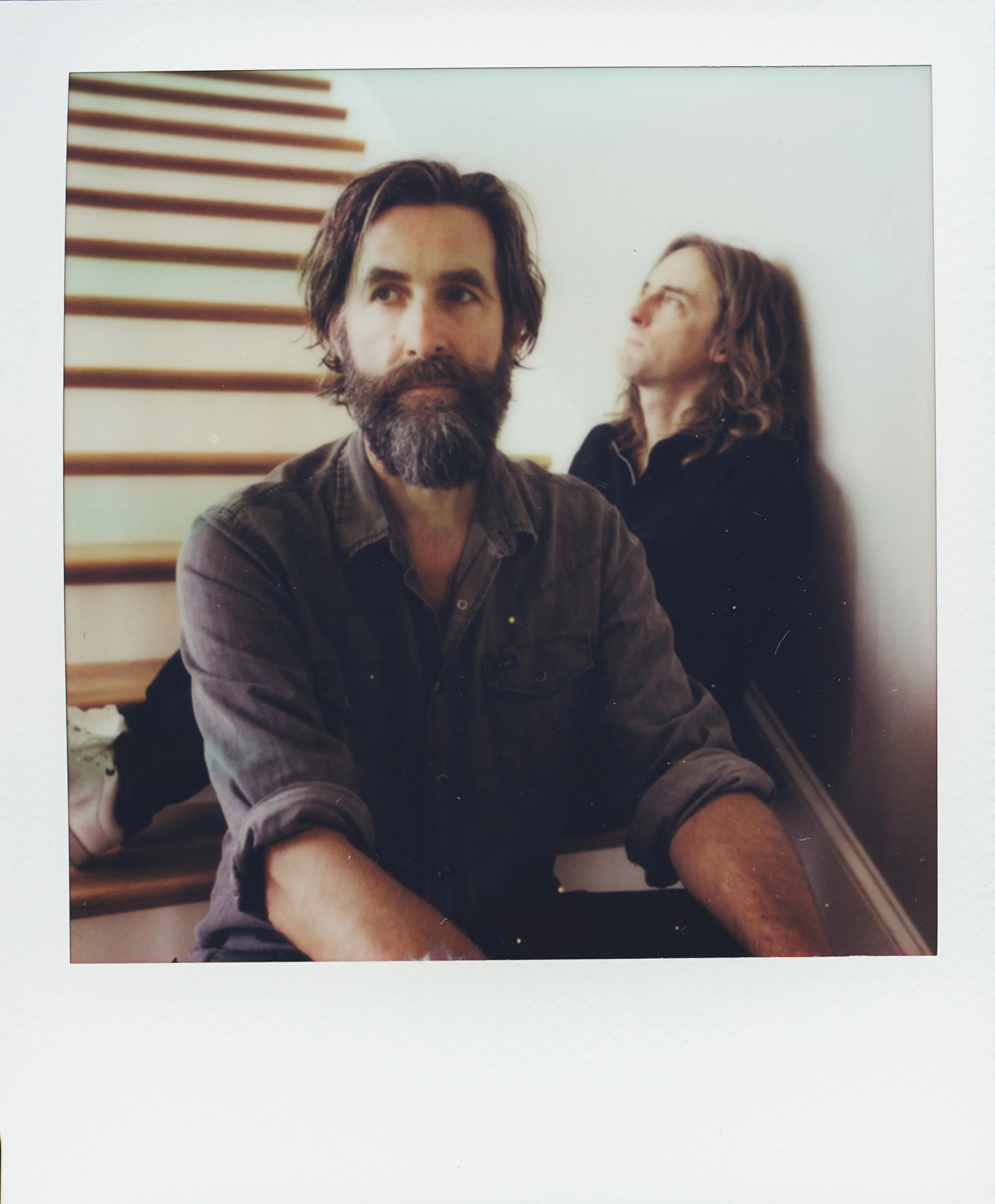 Polaroid portrait of musicians Tyler Ramsey and Carl Broemel sitting together on wooden stairs, captured for their collaborative album Celestin by Parker J. Pfister.
