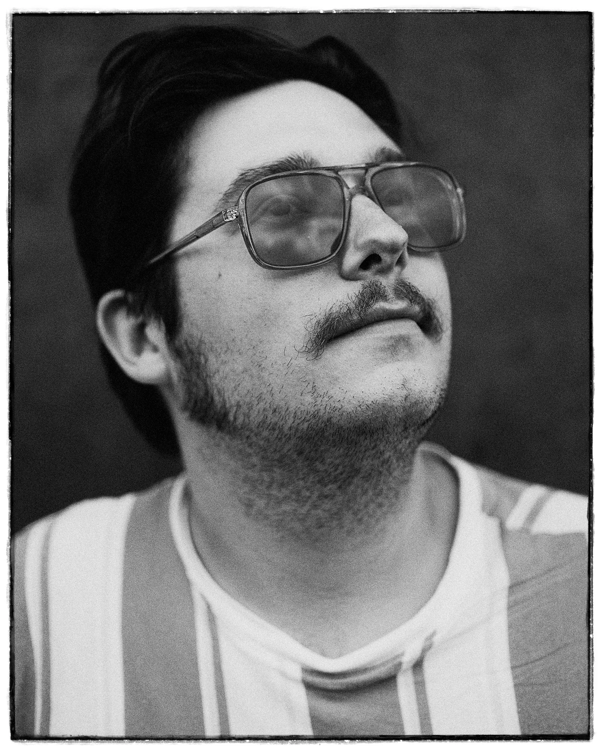 Black and white portrait of blues musician Eddie 9V wearing glasses and suspenders, photographed by Parker J. Pfister.