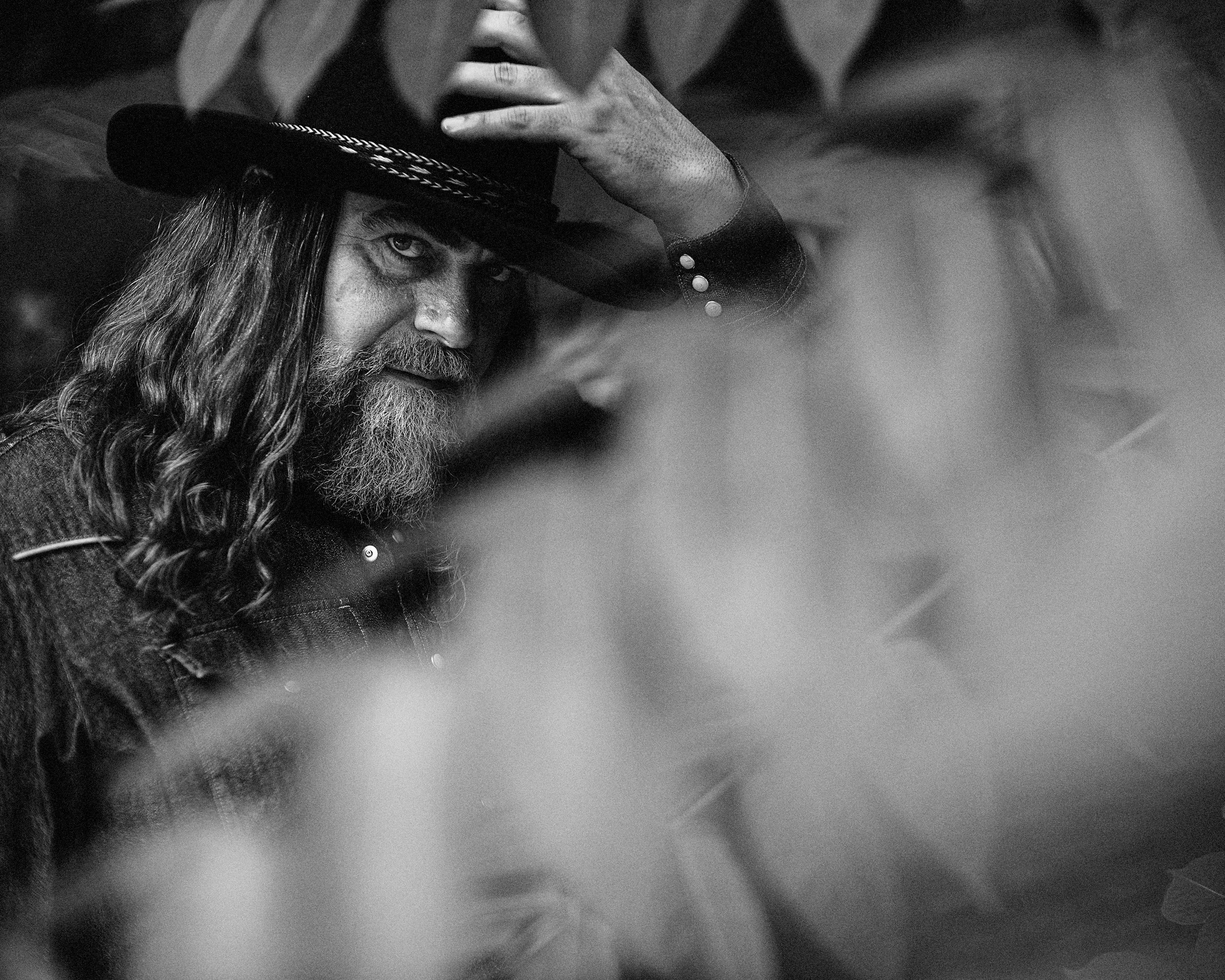 Black and white fine art portrait of musician Jake Smith, known as The White Buffalo, framed by foliage wearing a wide-brimmed hat, photographed by Parker J. Pfister.