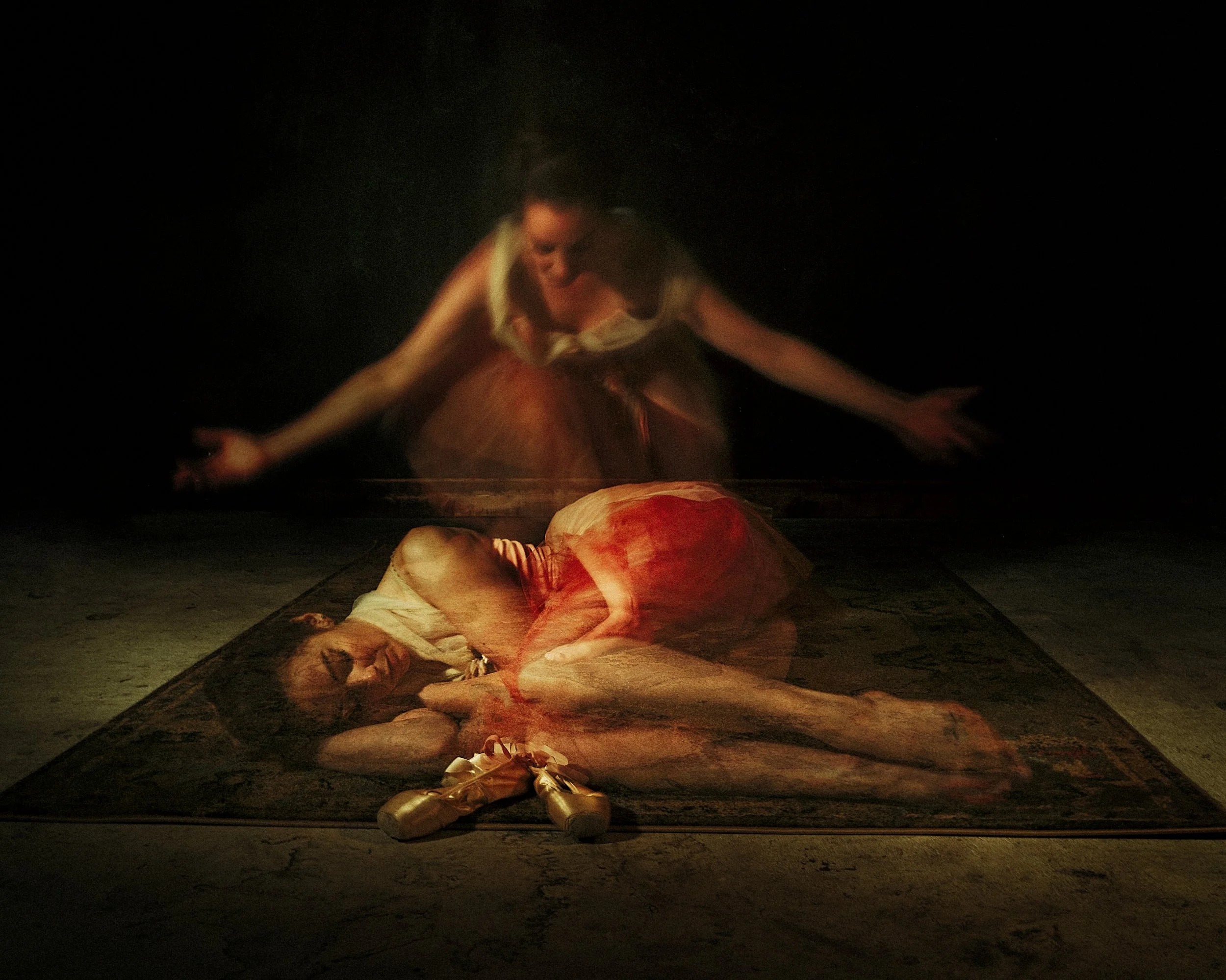 An atmospheric, dark black and white fine art image utilizing in-camera multiple exposures to show a ballerina collapsed on the floor, with a faint, expressive figure layered above her.