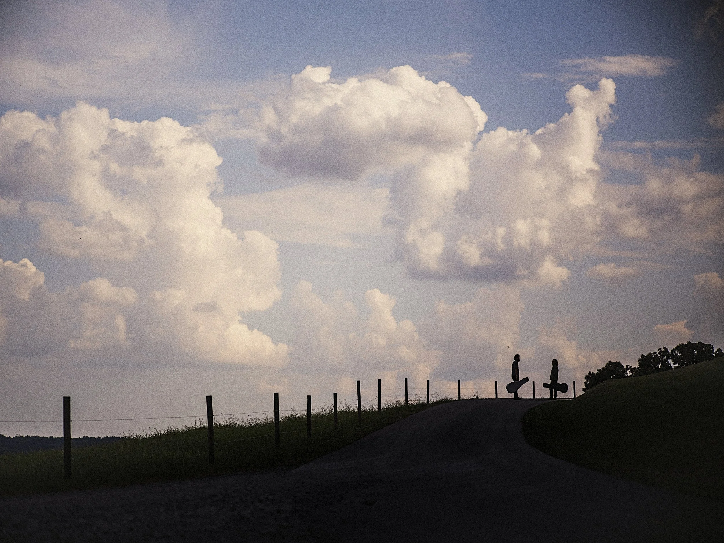Landscape photograph for the album Celestin by Tyler Ramsey and Carl Broemel, featuring a rural country road and wooden fence beneath dramatic clouds at Windy Hill Farm in Tennessee, captured by Parker J. Pfister.