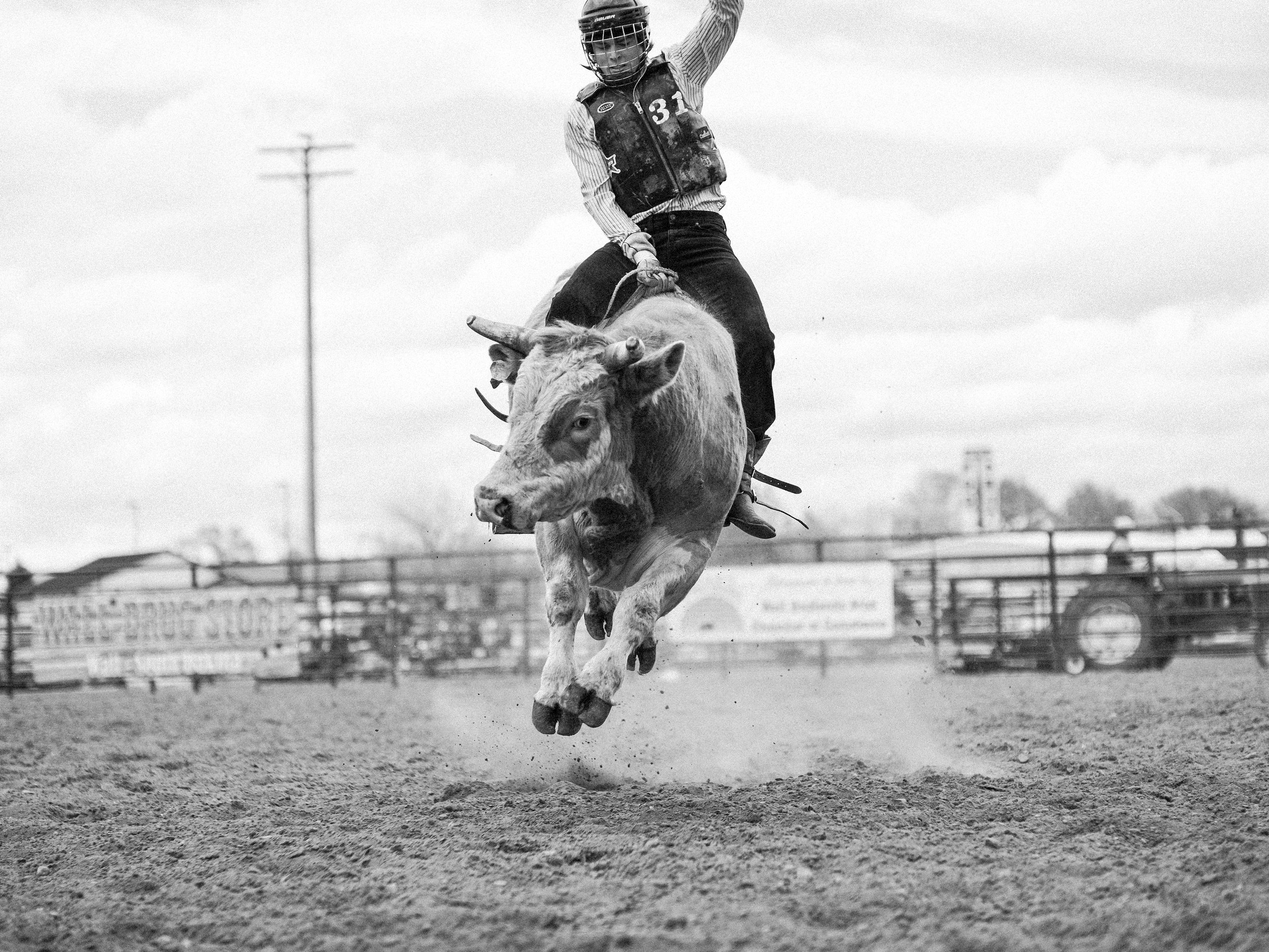 A high-contrast black and white portrait of a bull rider in Philip, South Dakota, capturing the intense focus, quiet gravity, and adrenaline before a ride.