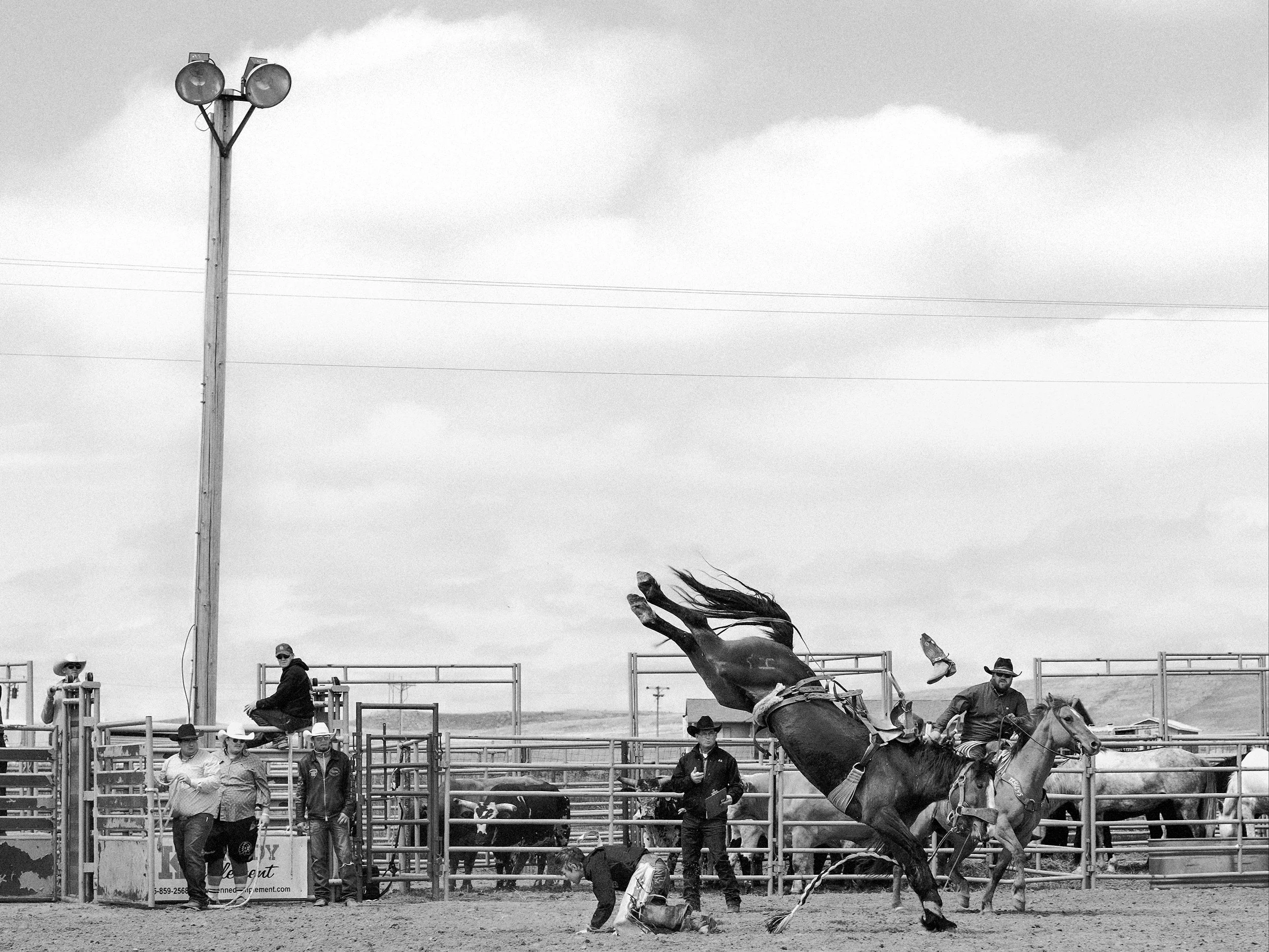 A heavy, high-contrast black and white documentary portrait capturing the raw character and quiet tension of a participant at the rodeo in Philip, South Dakota. boot in the air.
