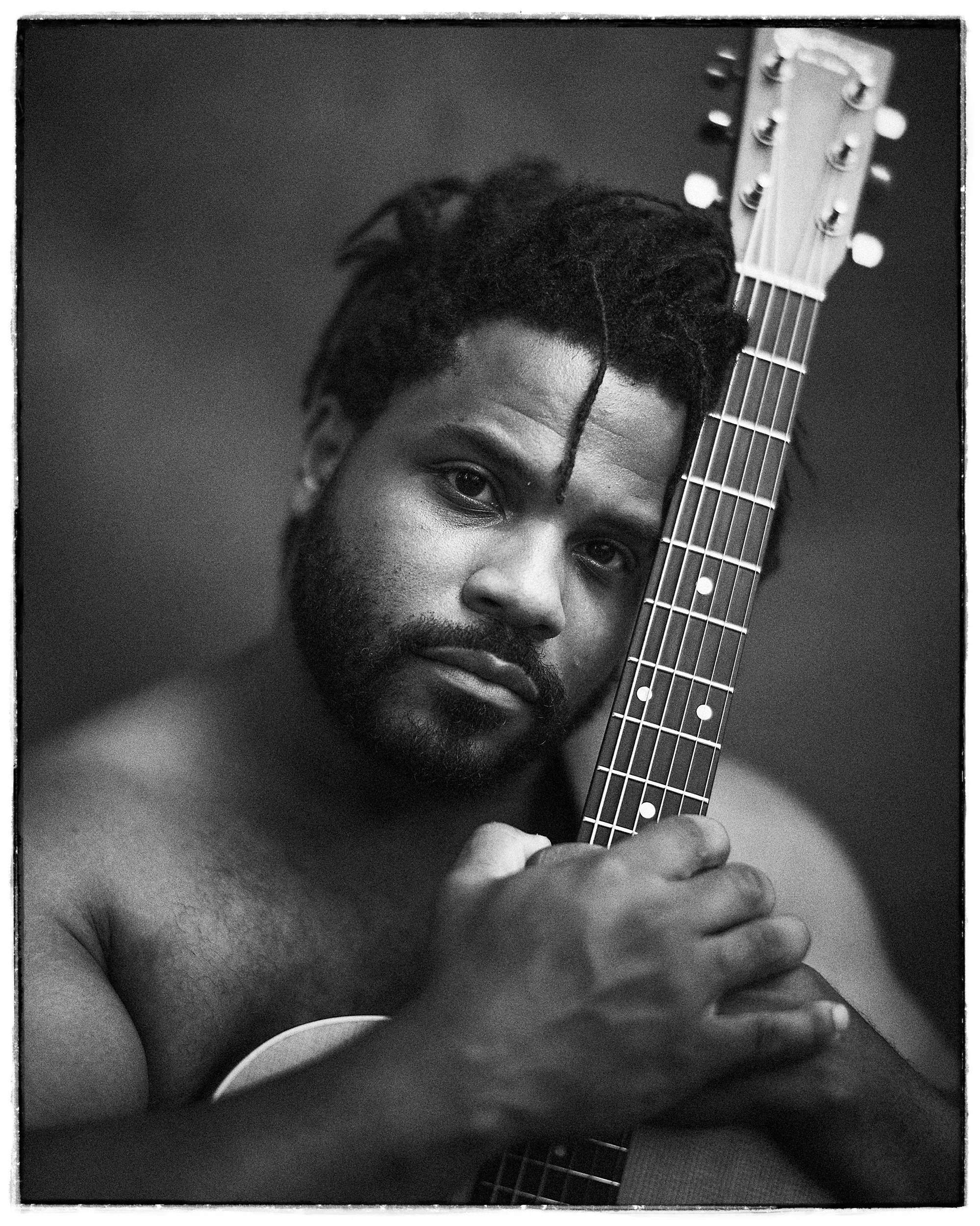 Striking black and white portrait of folk and Americana singer-songwriter Scott T. Smith holding an acoustic guitar, photographed by Parker J. Pfister.