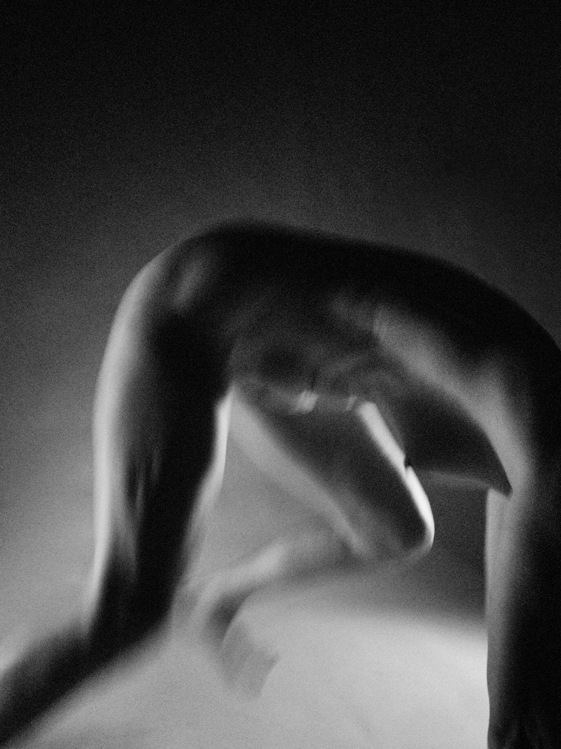 An atmospheric, glowing black and white fine art nude study of a reclining figure, utilizing an alternative oil filter process to soften focus and create a radiant light effect.