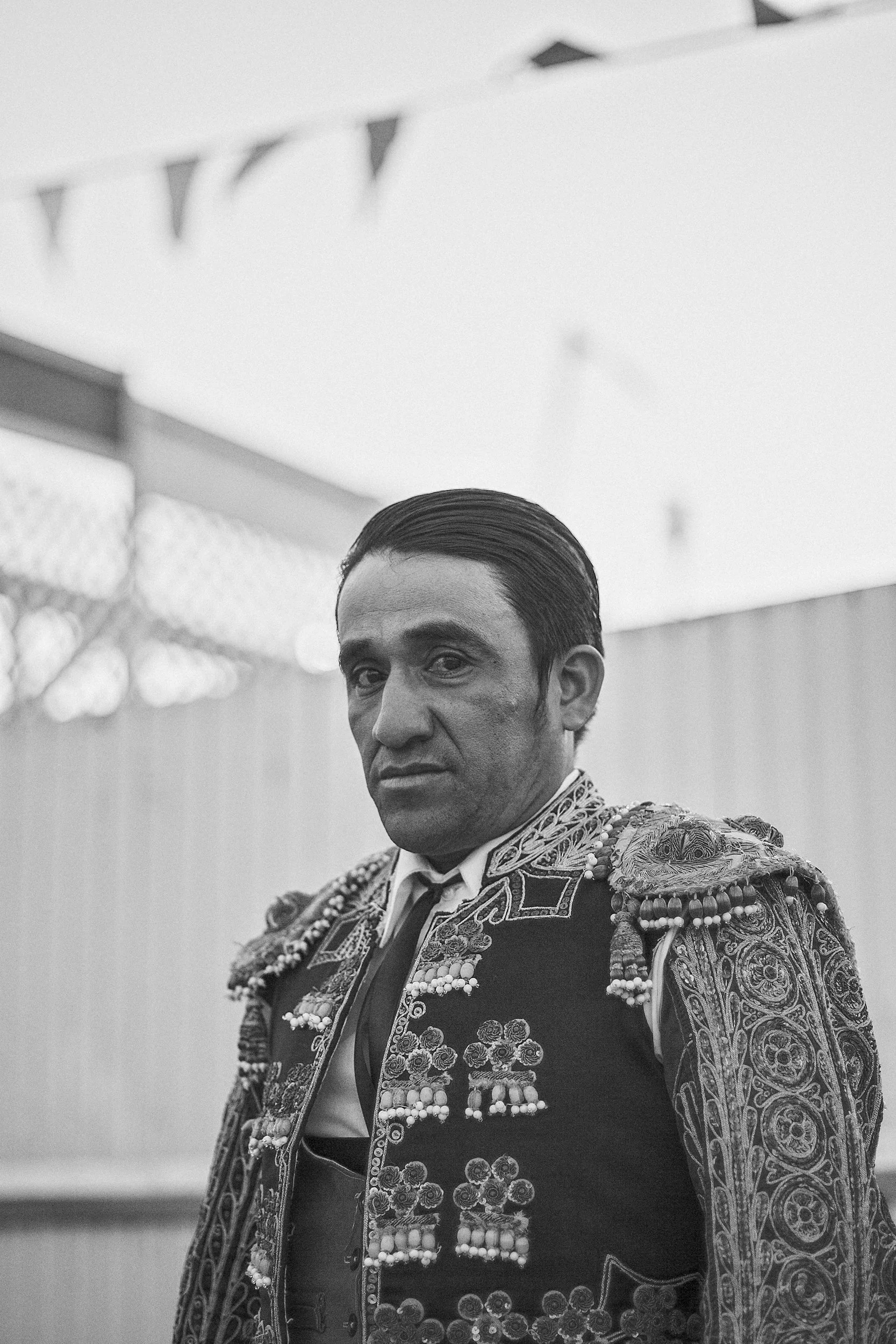 A heavy, high-contrast black and white portrait of a matador in Mexico, capturing the quiet gravity and raw intensity in his expression before entering the arena.