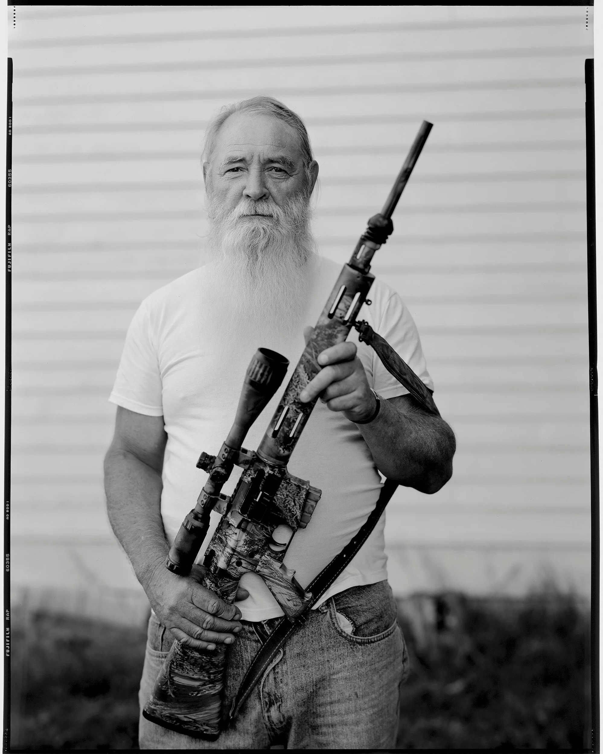 Fine art black and white 8x10 large format film portrait of a bearded man in a white t-shirt holding a rifle in Southern Ohio
