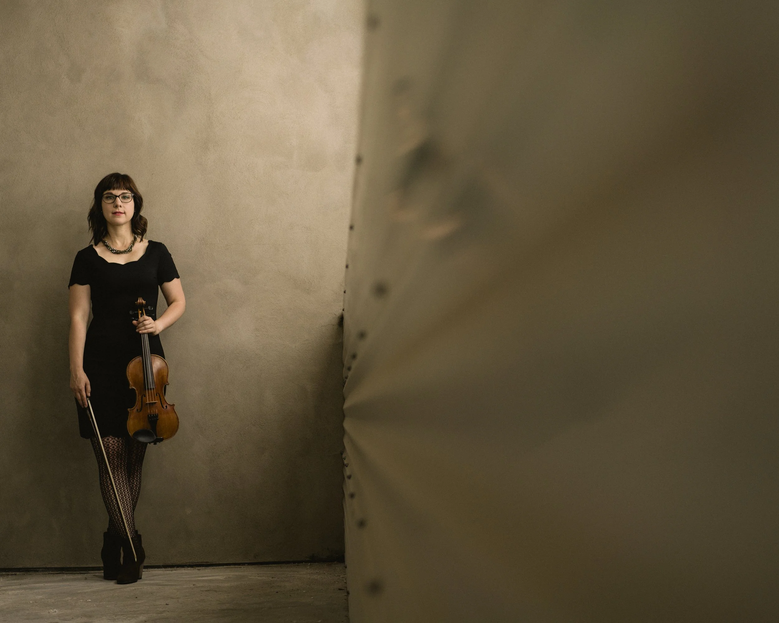 Fine art portrait of musician and fiddle player extraordinaire April Verch standing with her violin against a neutral studio backdrop, photographed by Parker J. Pfister.