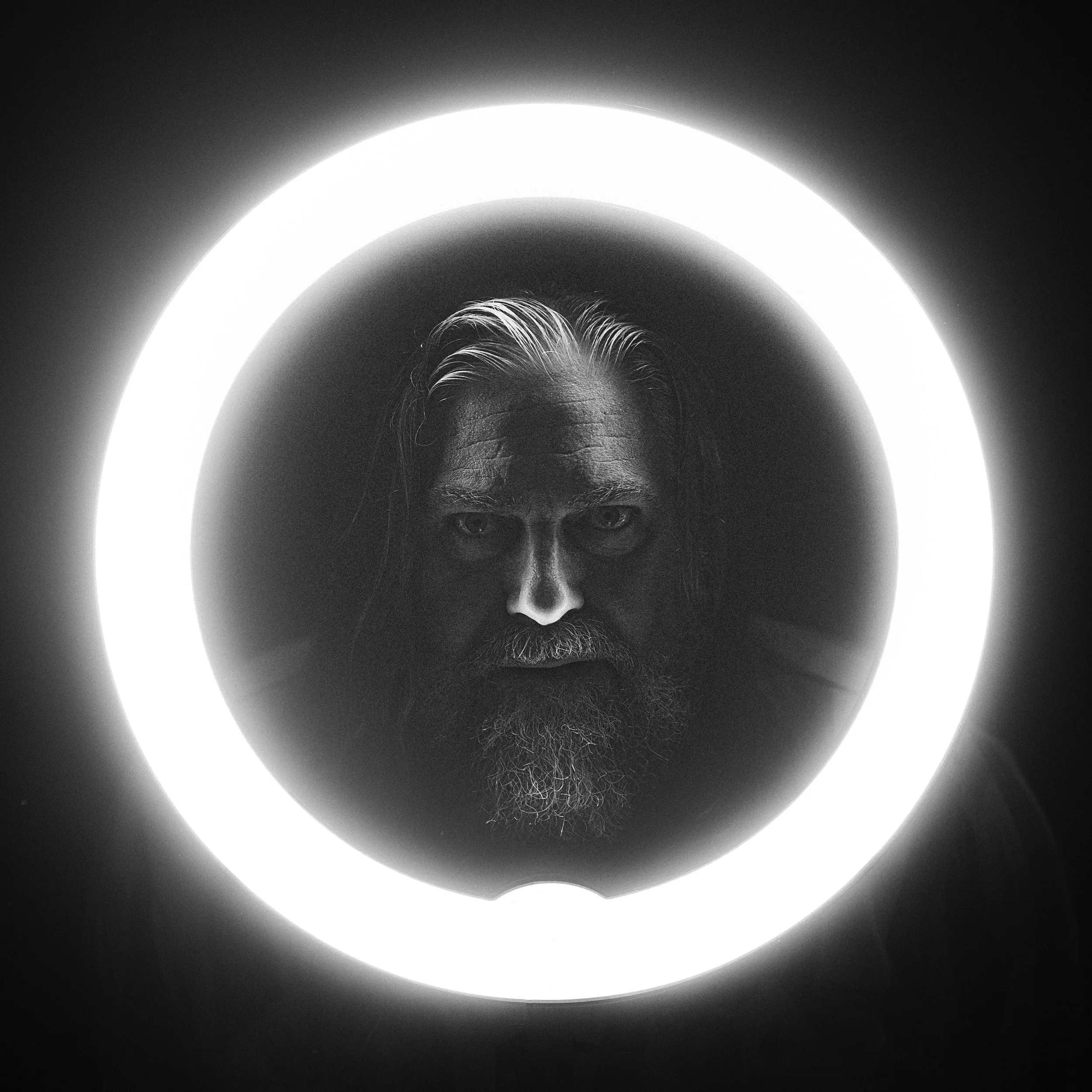 Black and white portrait of musician Jake Smith, known as The White Buffalo, framed within a glowing ring light, photographed by Parker J. Pfister.