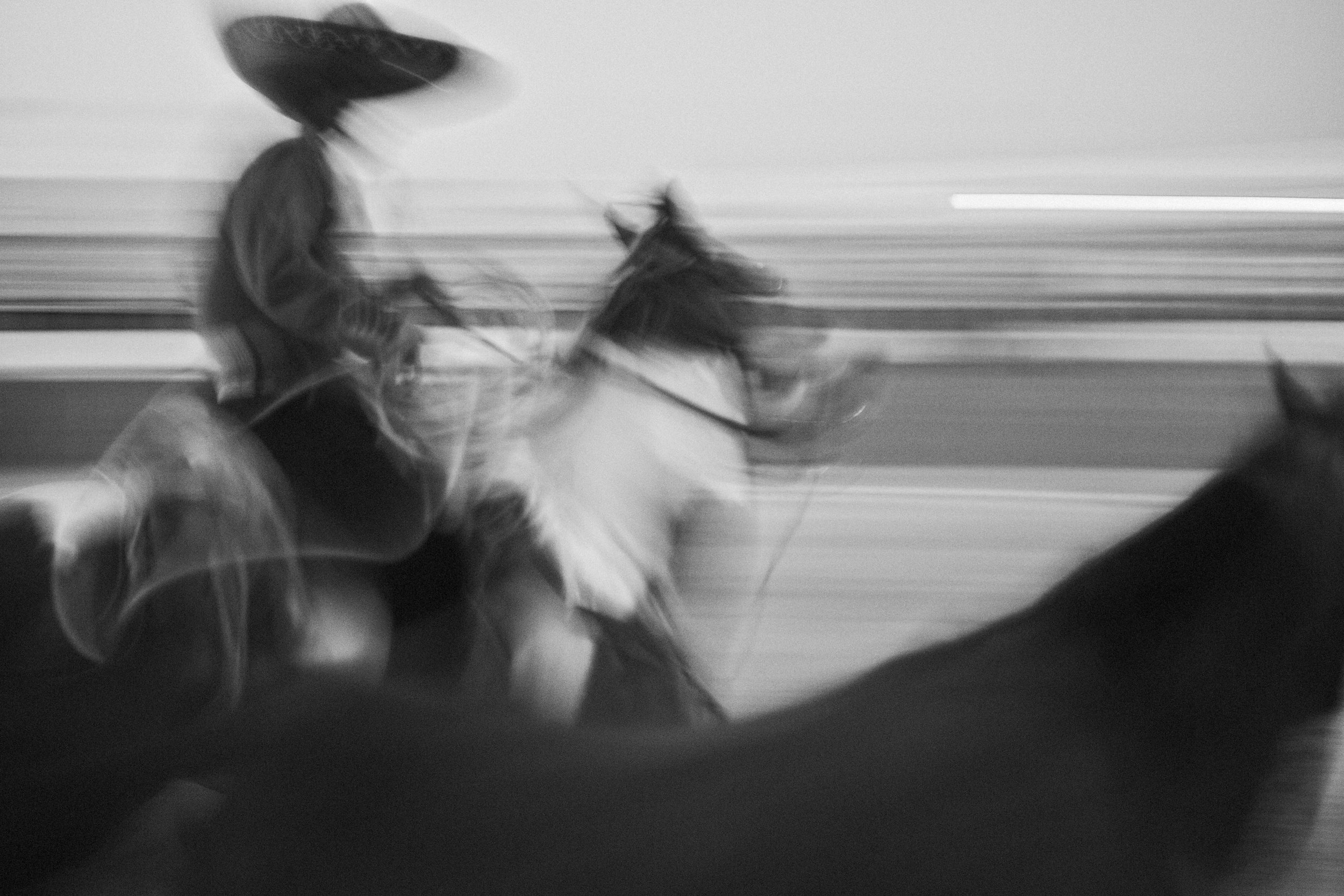 A gritty, personal black and white documentary photograph from behind the chutes at an arena in Mexico, focusing on the heavy atmosphere before the gates open.