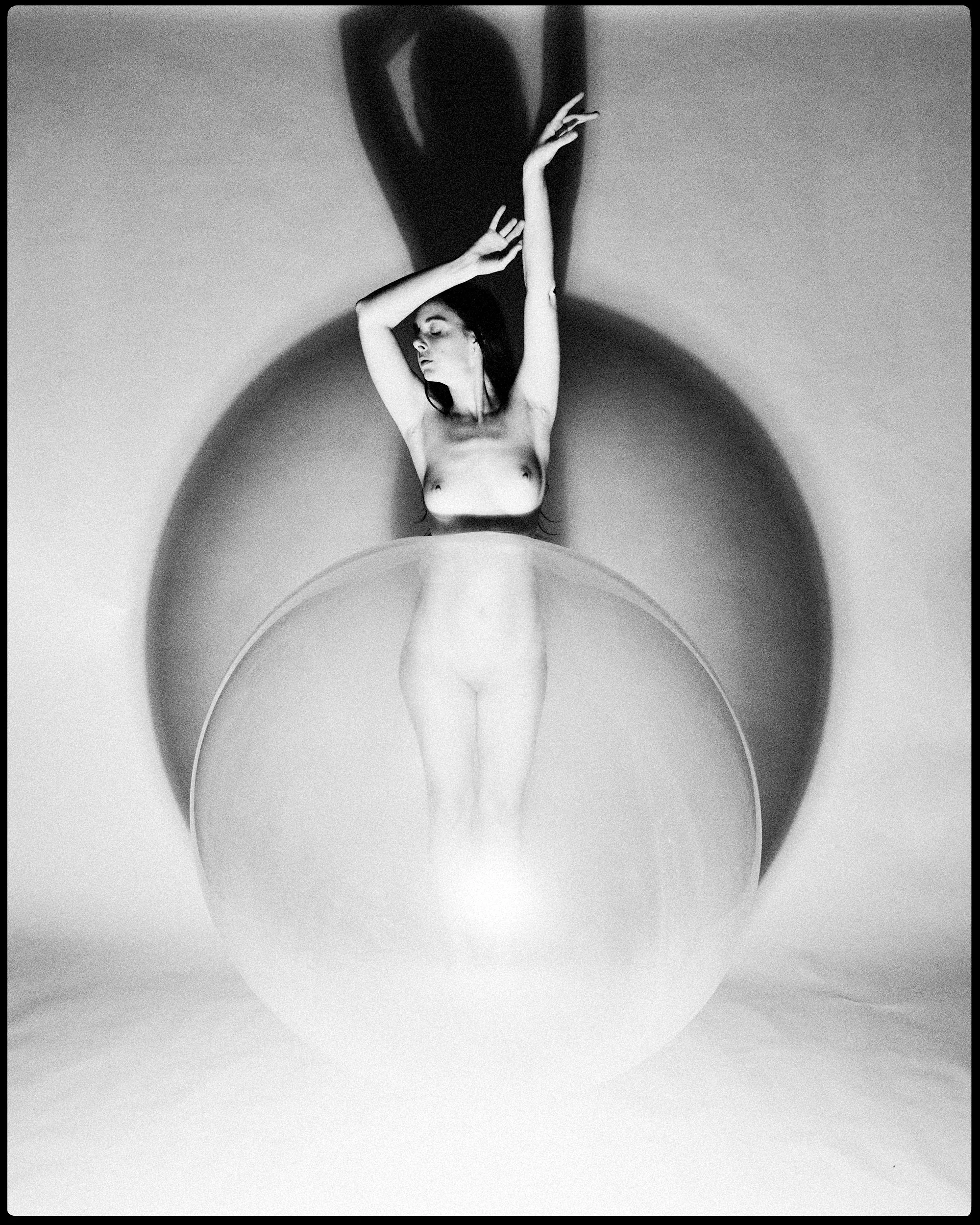 An expressive fine art portrait focusing on high-contrast lighting, clean lines, and geometric circles that highlight the form and shadow of the nude subject.