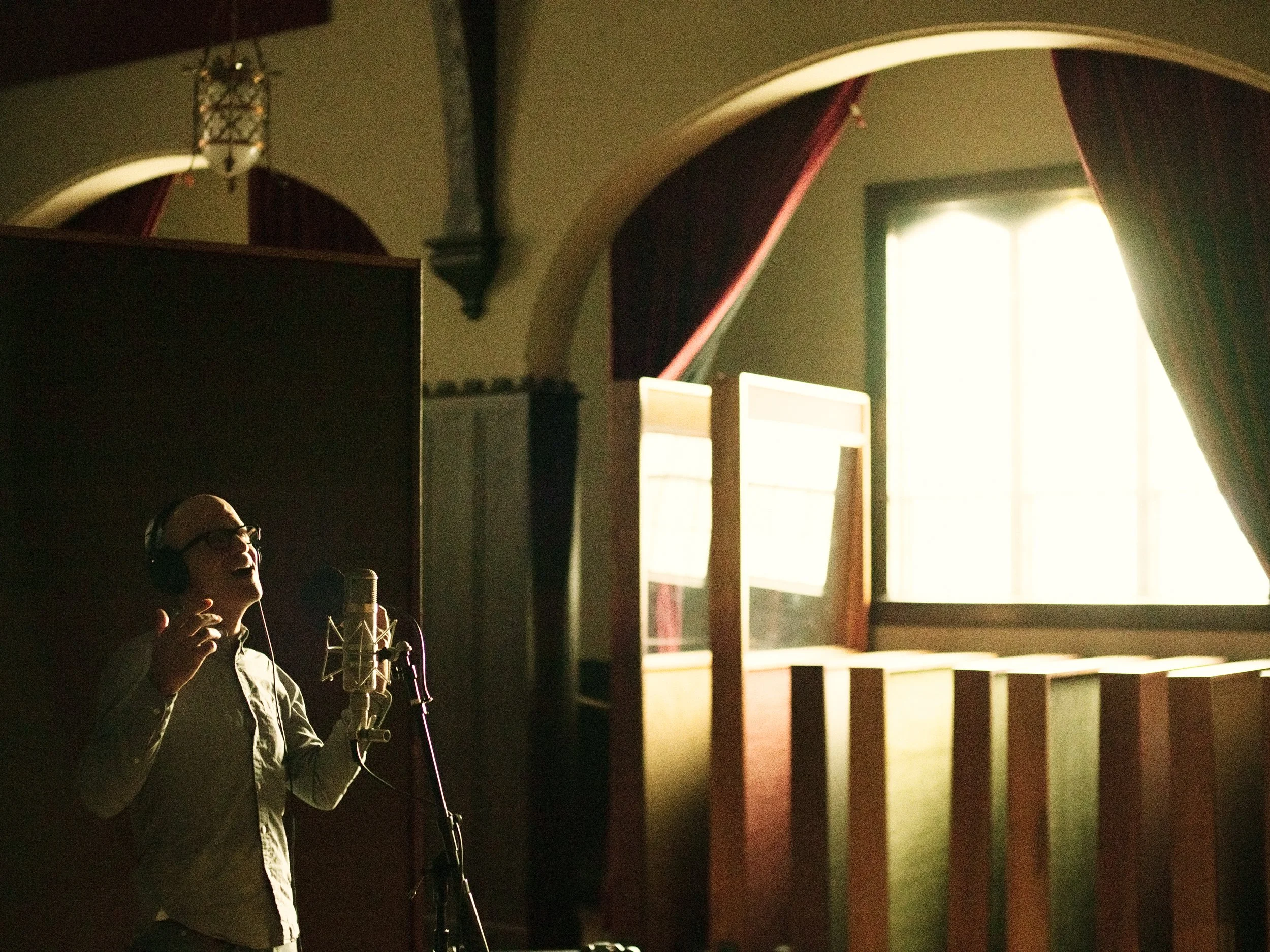Atmospheric photo of musician Gary Jules singing into a microphone during a studio recording session at Echo Mountain Recording in Asheville, NC, photographed by Parker J. Pfister.