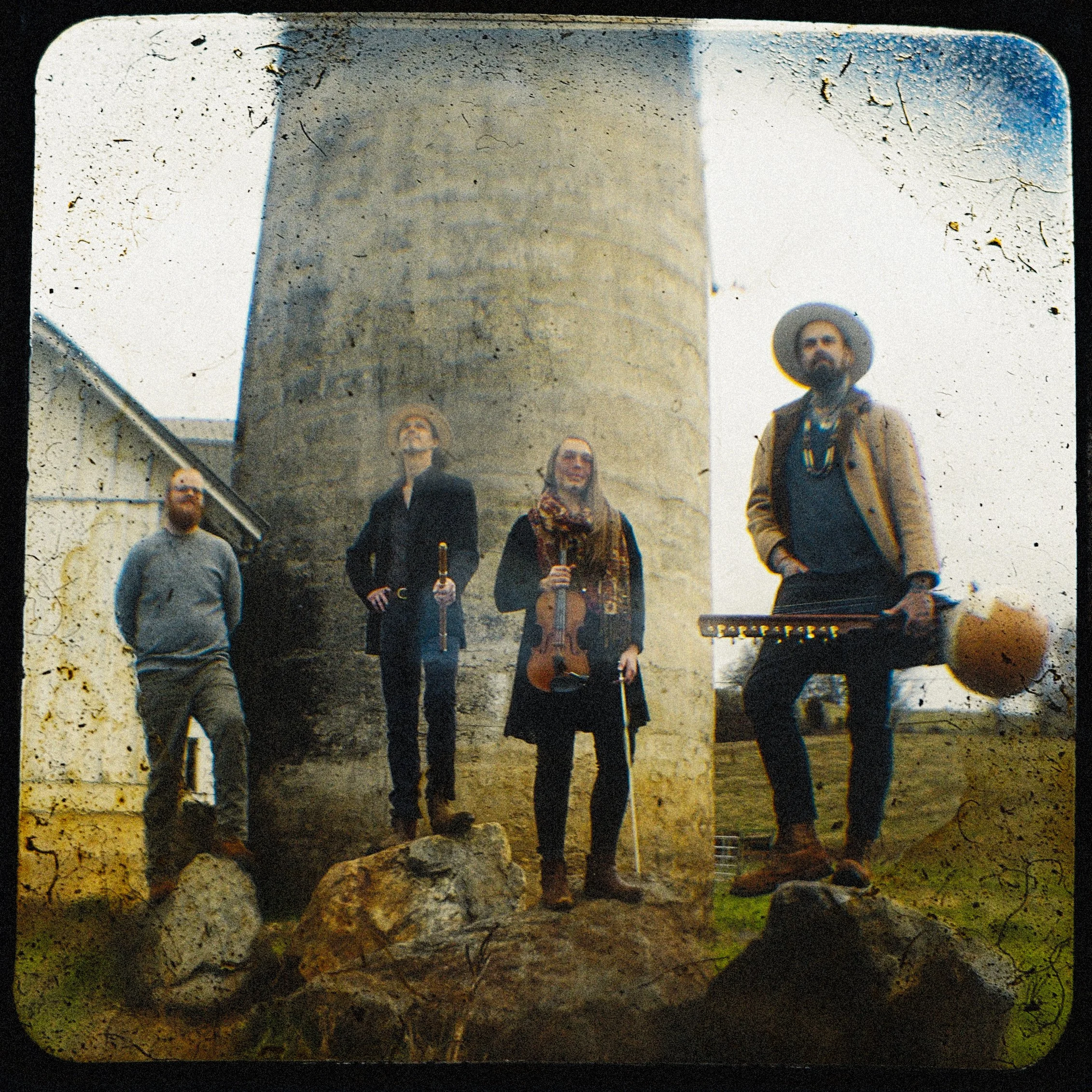 Textured color portrait of Western North Carolina band Life Like Water standing outside by a stone tower, captured using a custom handmade Through-the-Viewfinder (TtV) camera system by Parker J. Pfister.