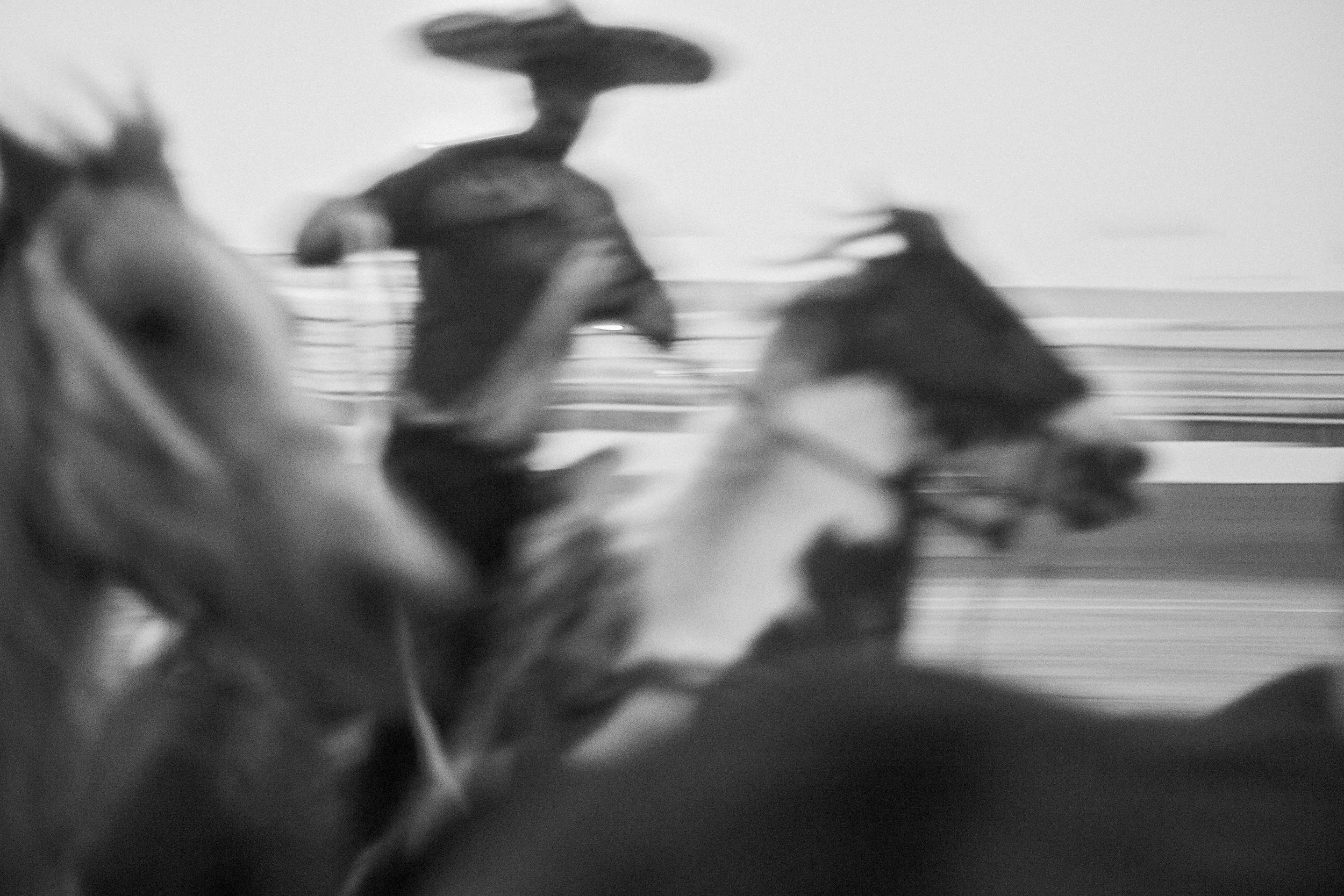 A documentary image tracking the fast-paced motion and quiet tension of riders and stock enveloped in dust under the lights of a Mexican arena.