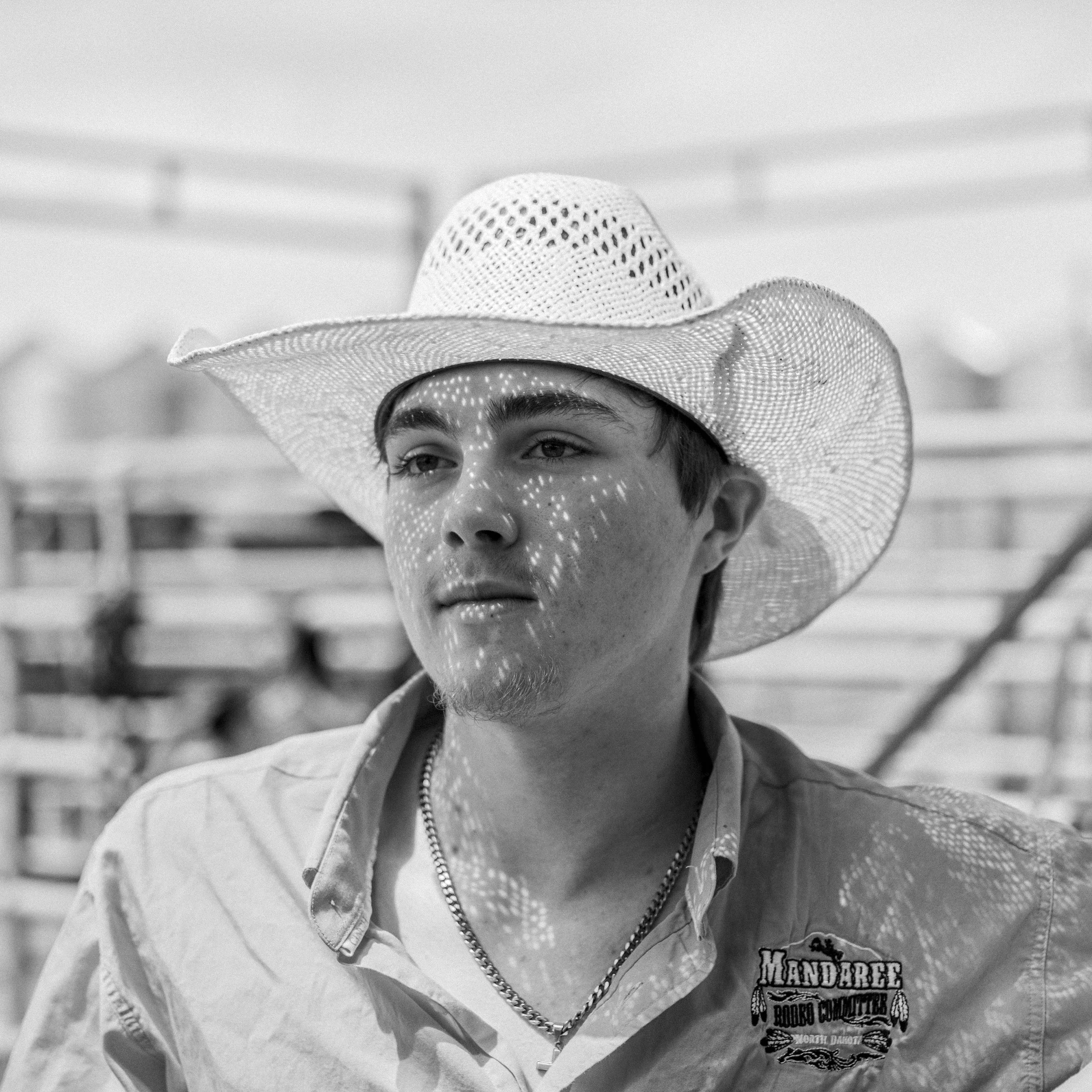 A portrait-heavy documentary image focusing on the unvarnished characters and weathered faces of the community at a South Dakota rodeo arena.